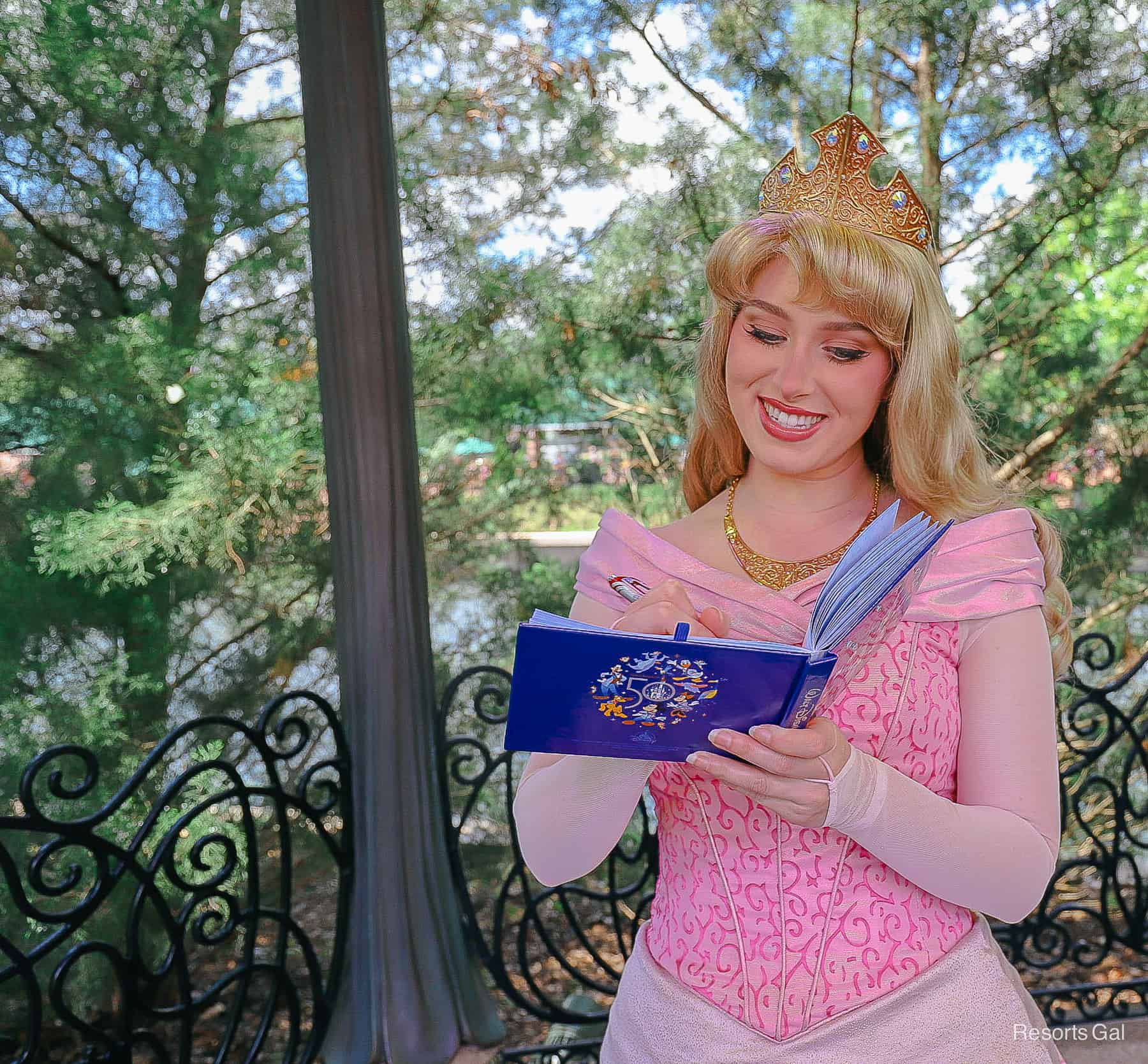 Aurora signs an autograph in her pink dress. 