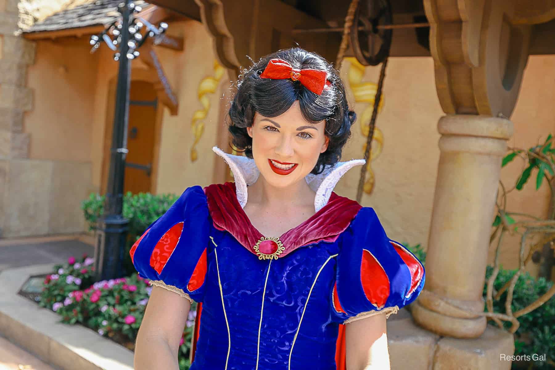Snow White standing in front of her wishing well at Epcot. 