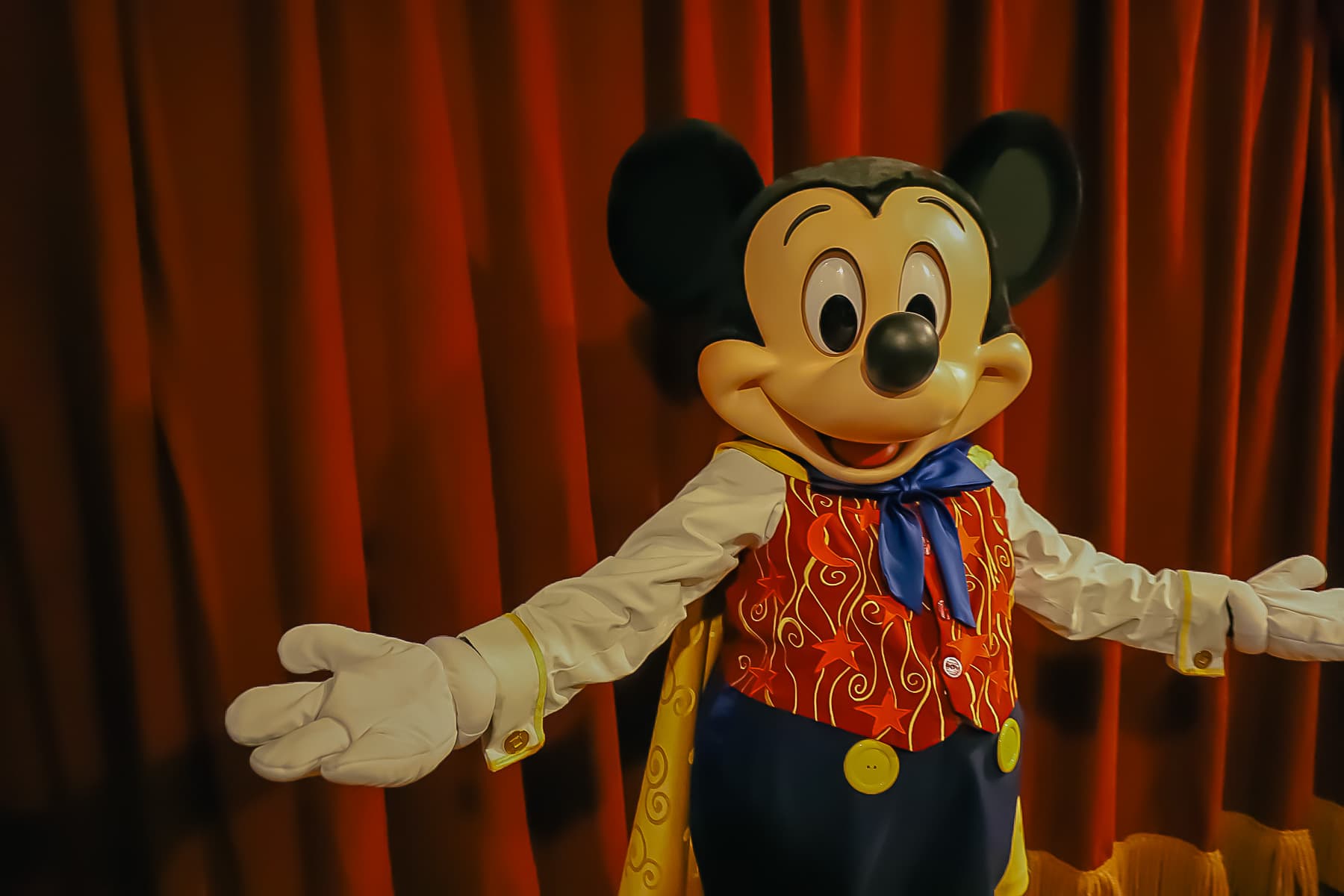 Mickey poses with both arms wide out. 
