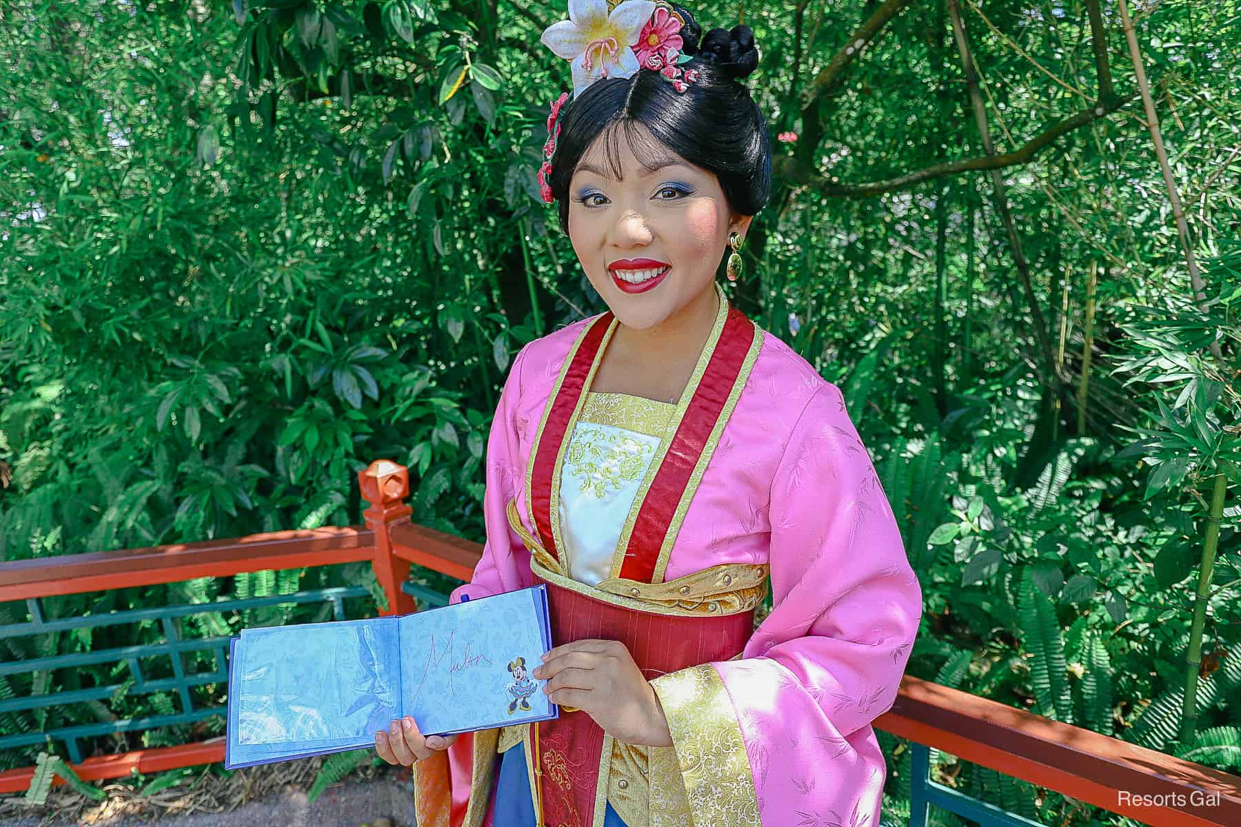 Mulan holds an autograph book. 