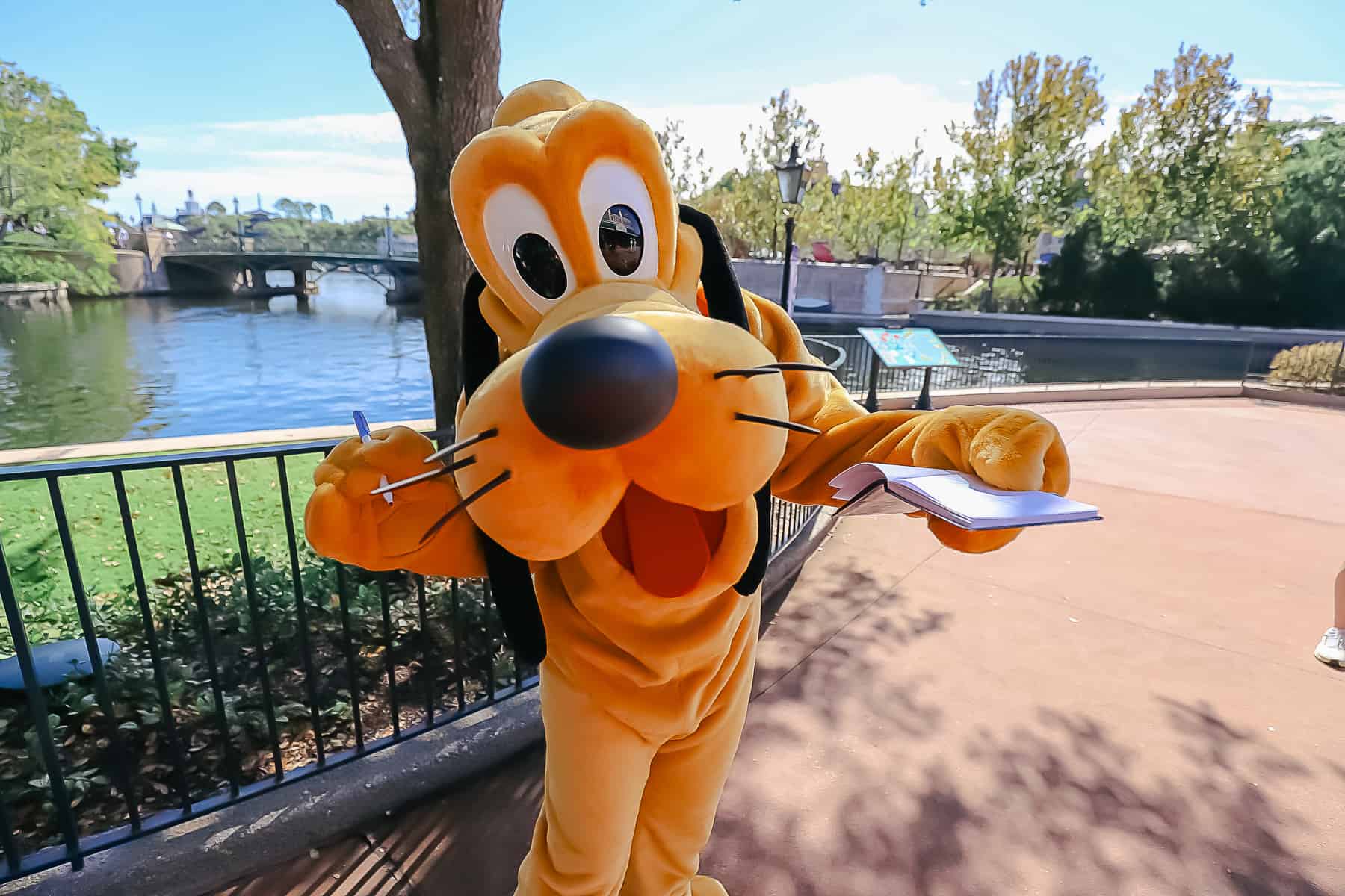 Pluto holding an autograph book and a pen. 