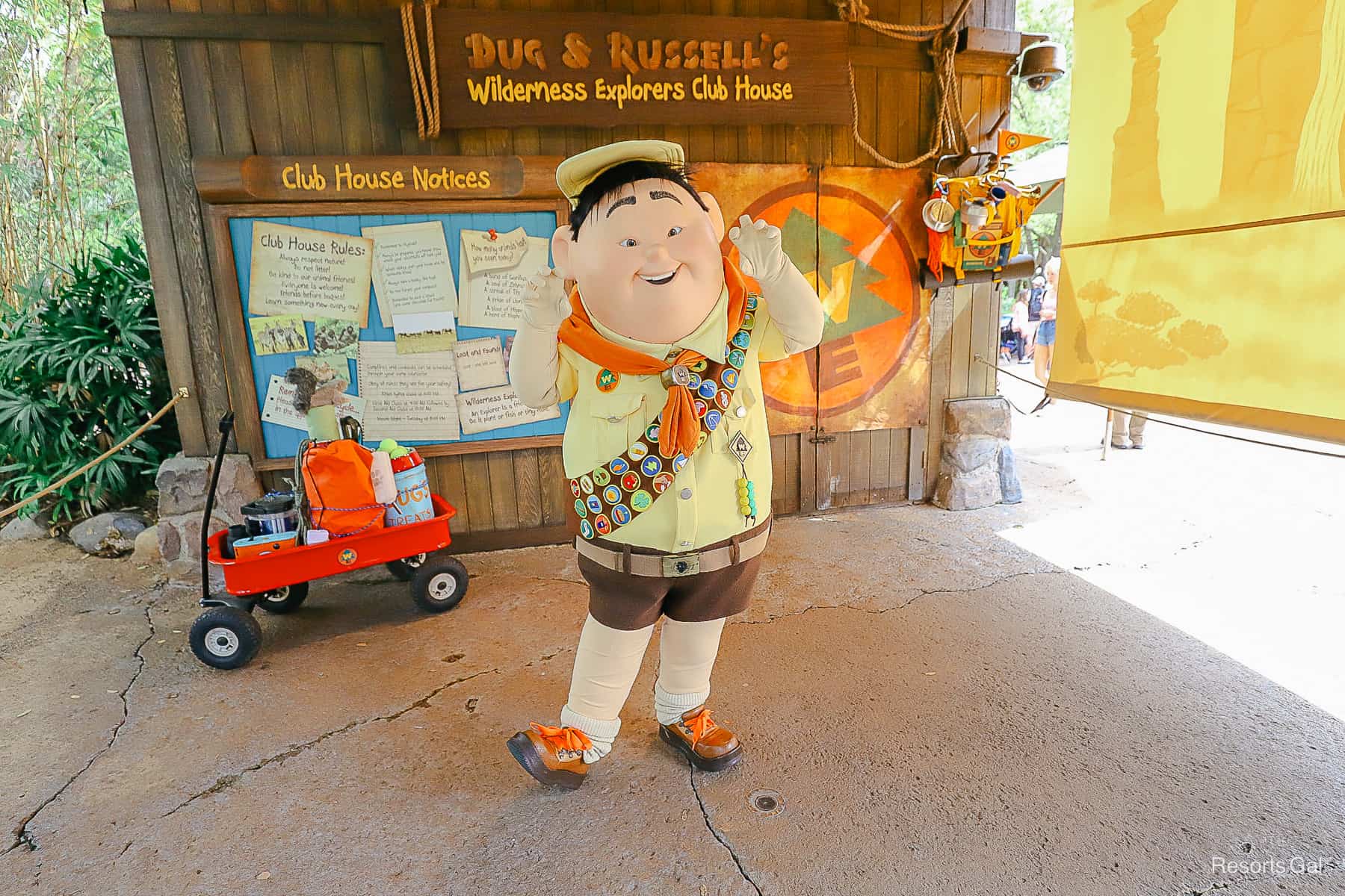 Russell posing for a photo with his foot kicked up and making the Wilderness Explorer sign. 