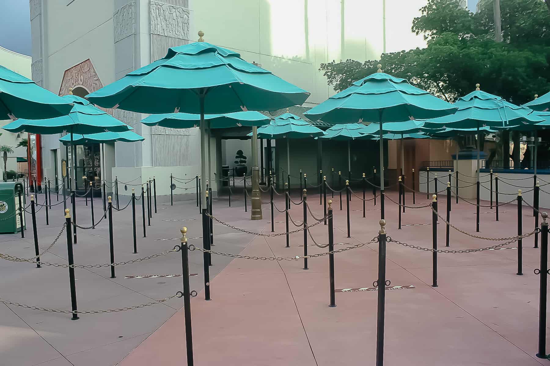 exterior portion of the queue with green umbrellas and chain ropes 