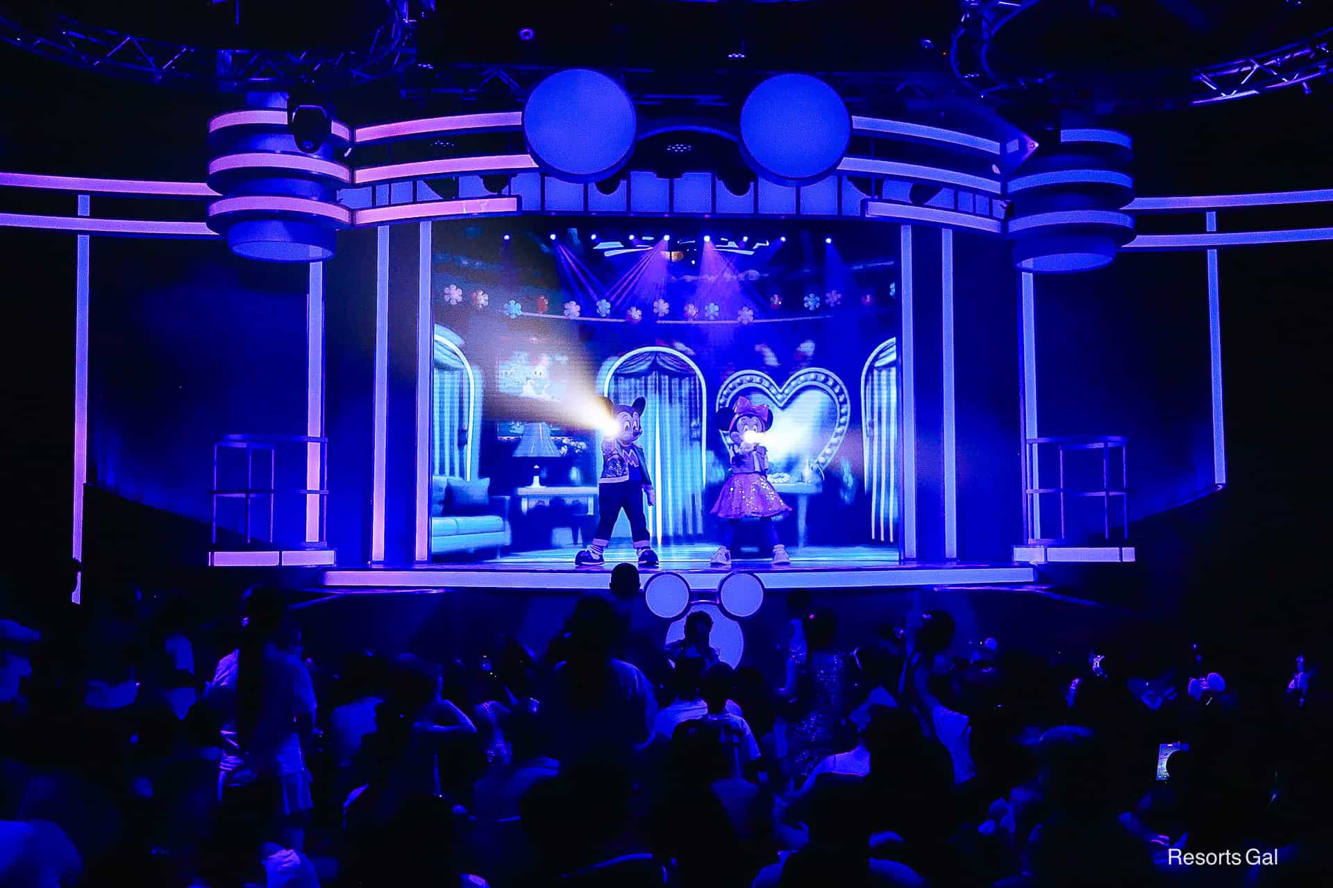the stage is dark and Mickey and Minnie Mouse have flashlights 