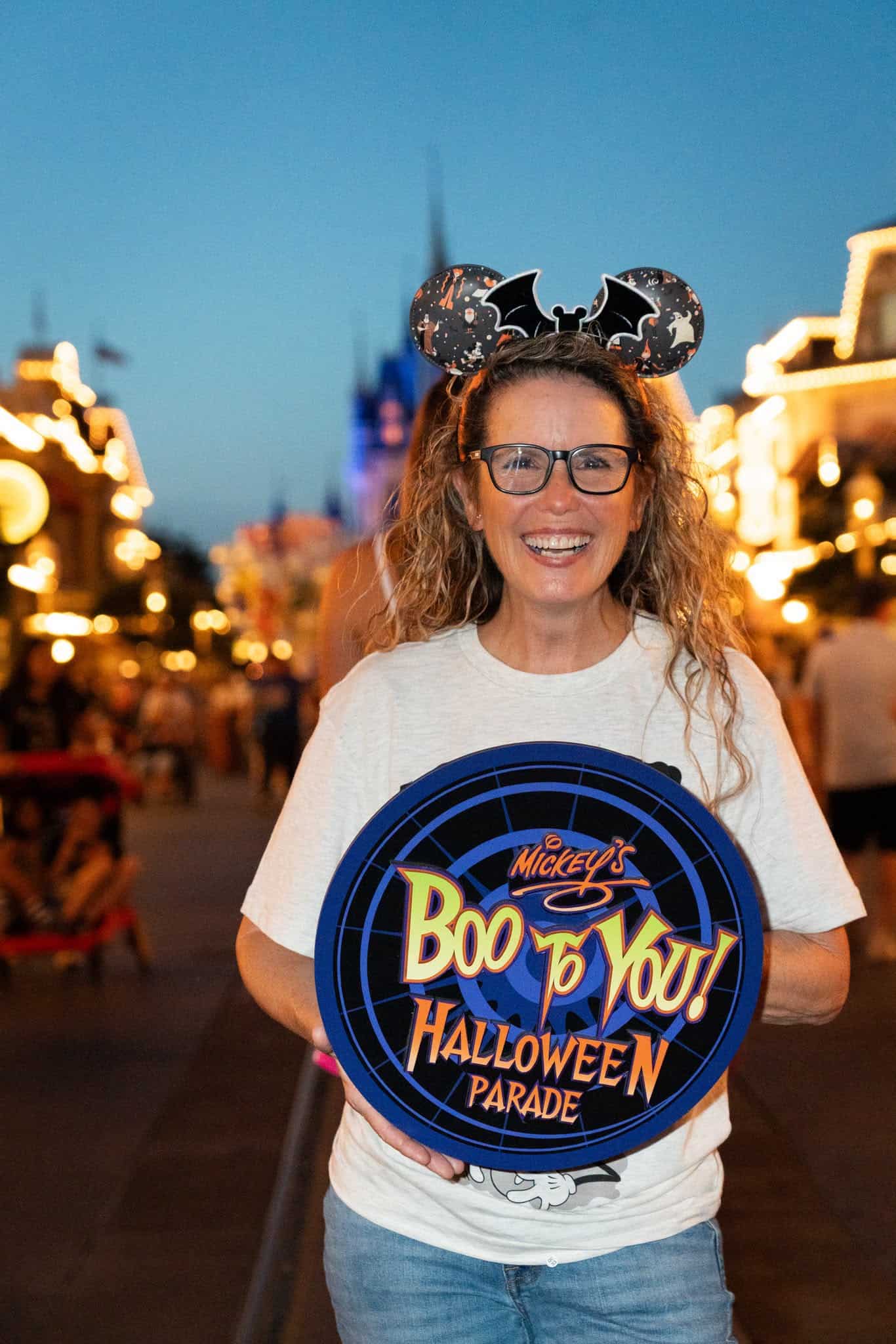 a guest holding a prop with Mickey's Boo To You Halloween Parade as an example of a PhotoPass Shot at the Party