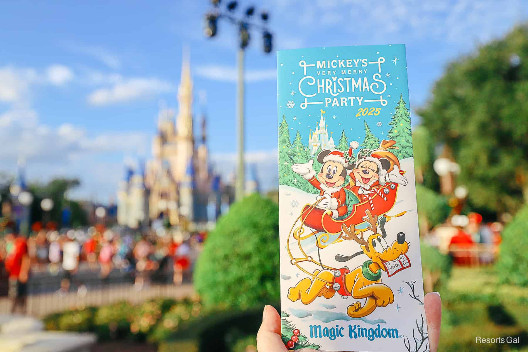 a hand holding up the Mickey's Very Merry Christmas Party 2025 party brochure with map