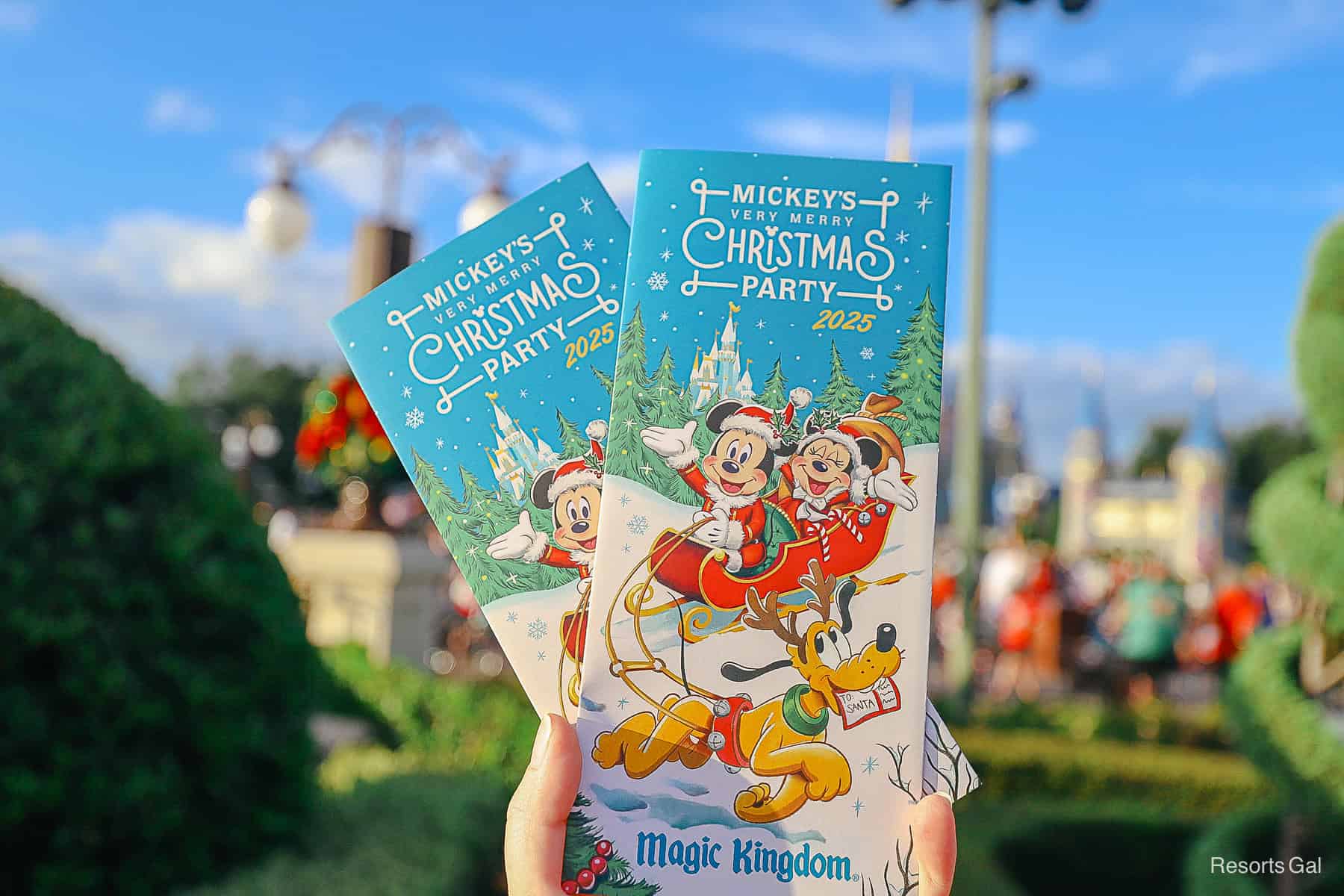 a hand holding up two 2025 party maps at Magic Kingdom