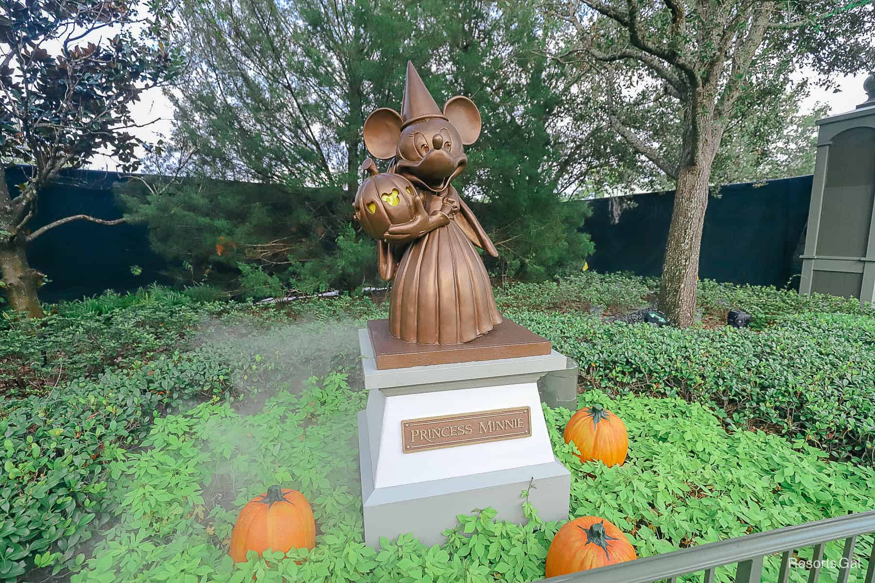 a statue of Minnie with a pumpkin with fog around it 