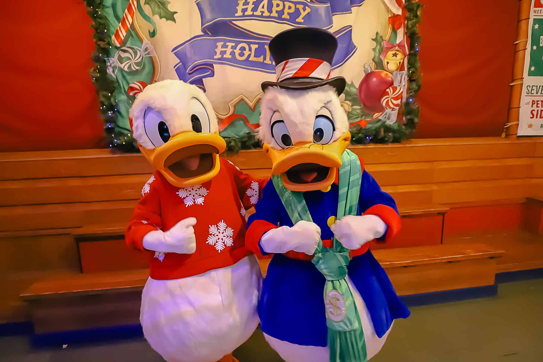 Donald Duck in a red sweater with snowflakes and Scrooge with a holiday scarf. 