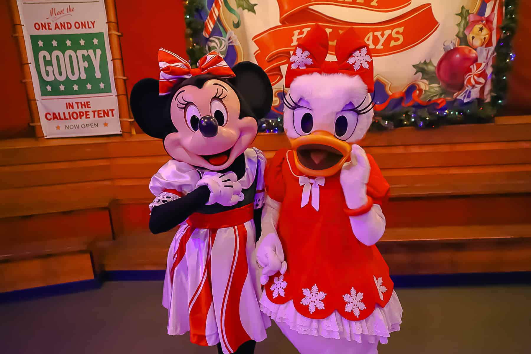 Minnie Mouse in a candy cane striped dress and Daisy in a red dress with snow flakes. 