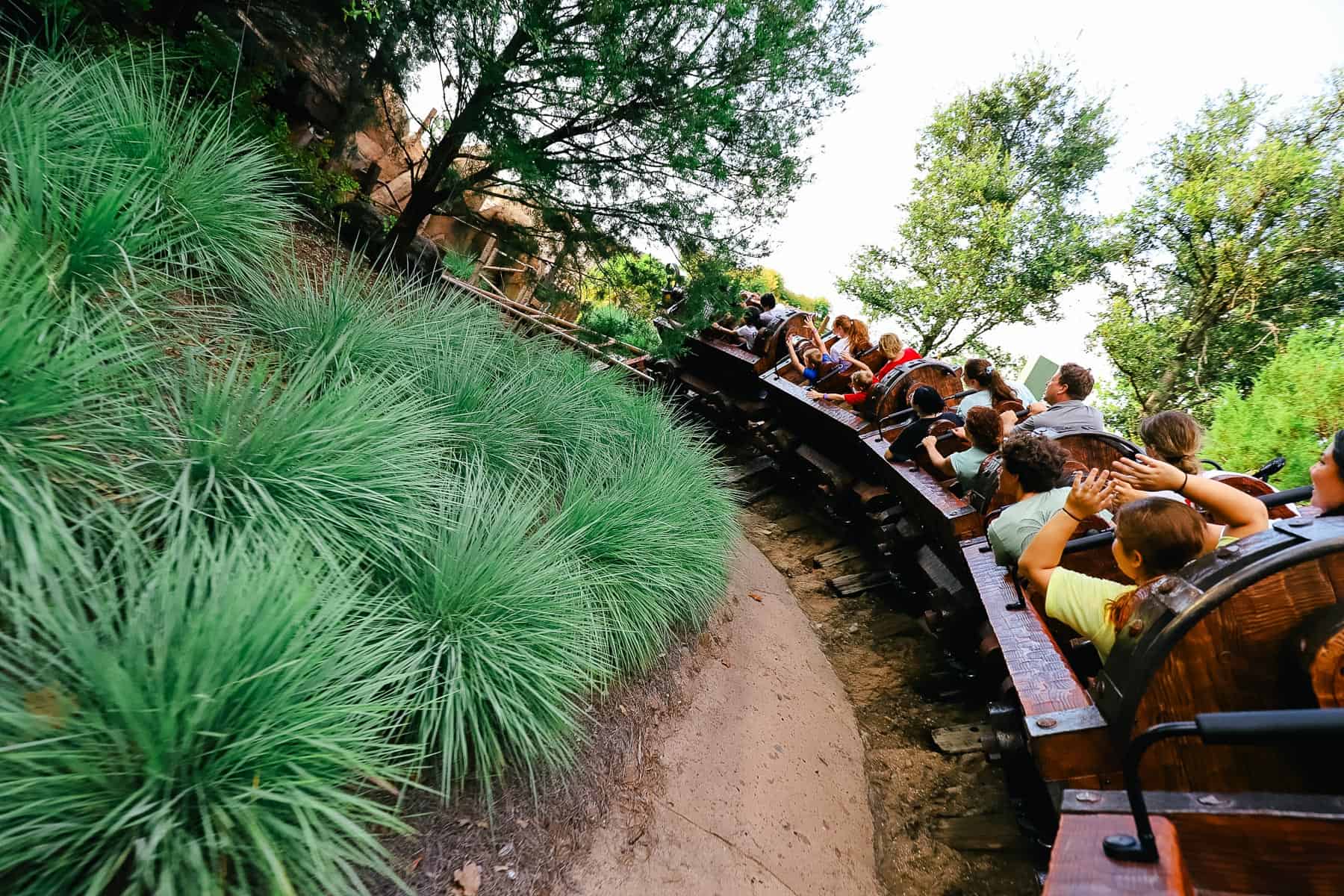 Guests with their arms up as they fly around a curve. 