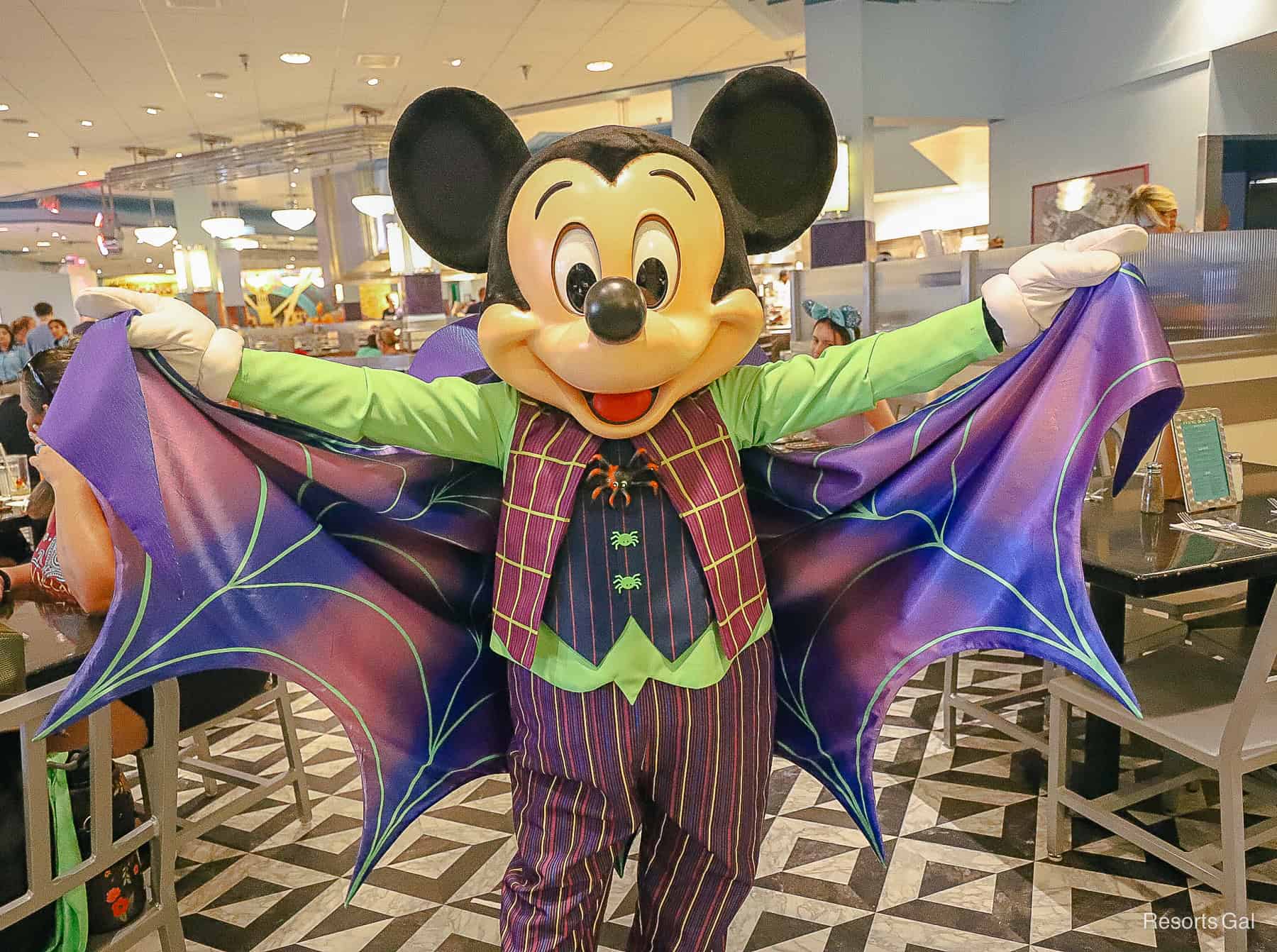 Mickey Mouse has a vampire outfit with spider web cape and spider buttons in purple and green. 