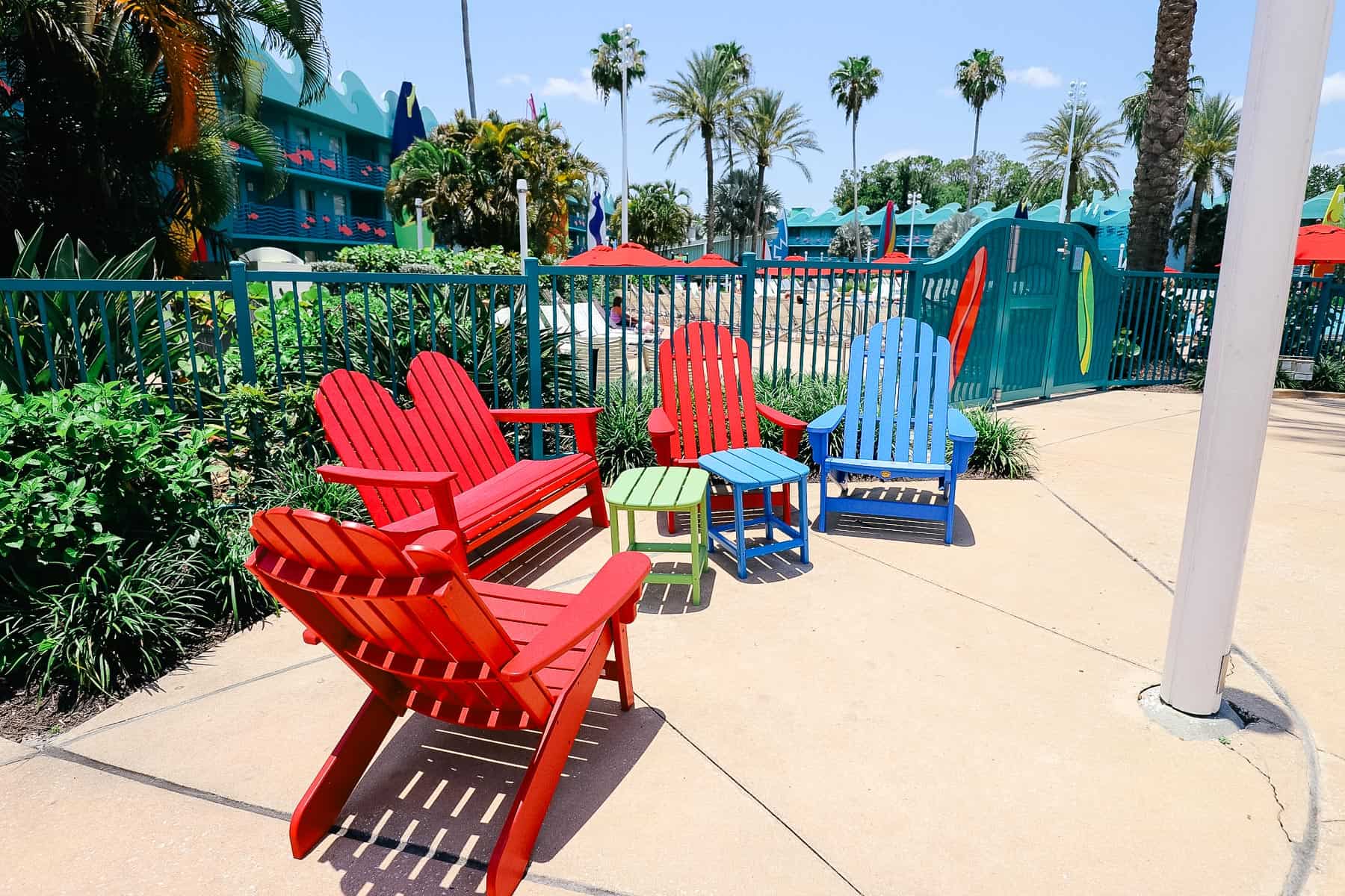 a group of red and blue Adirondack chairs near the pool 