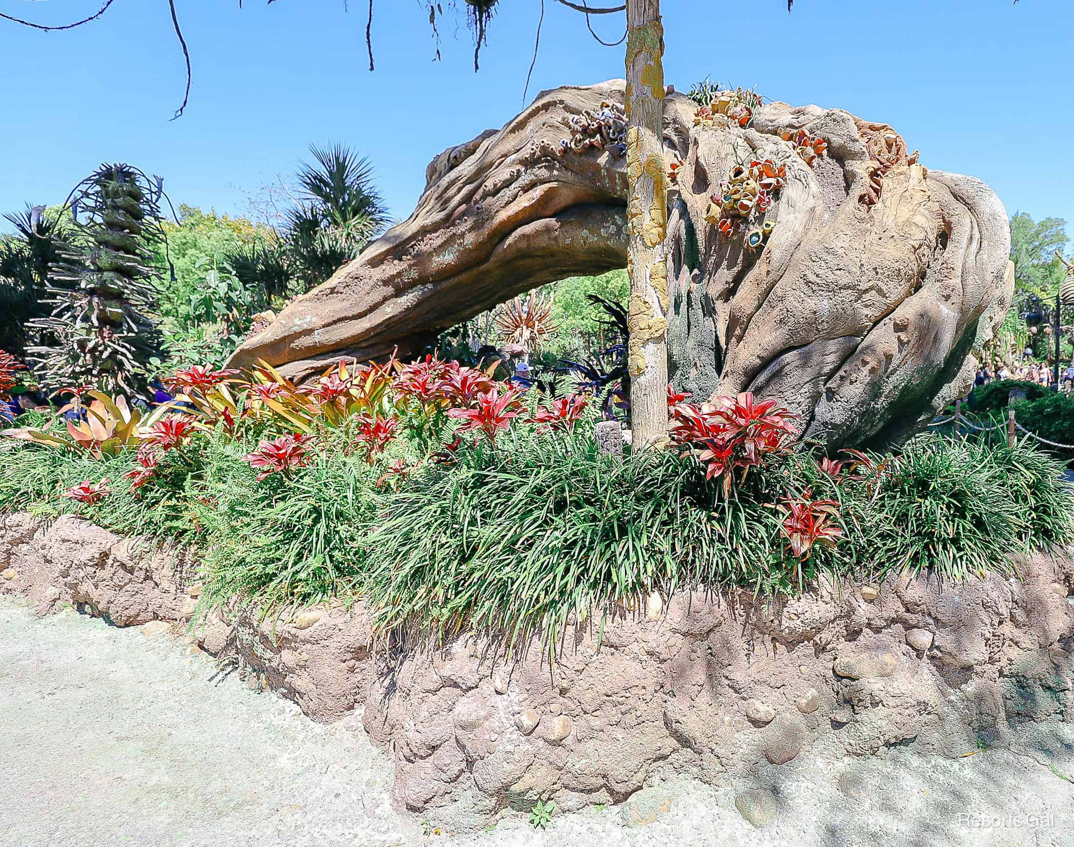 roots extending from the ground with red plants and other decor 