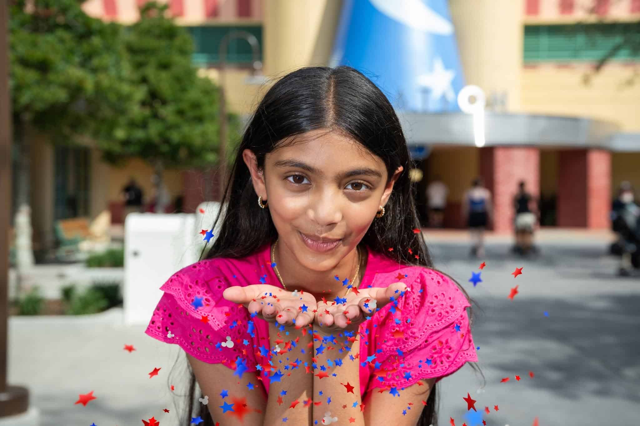 a girl blowing red, white, and blue confetti