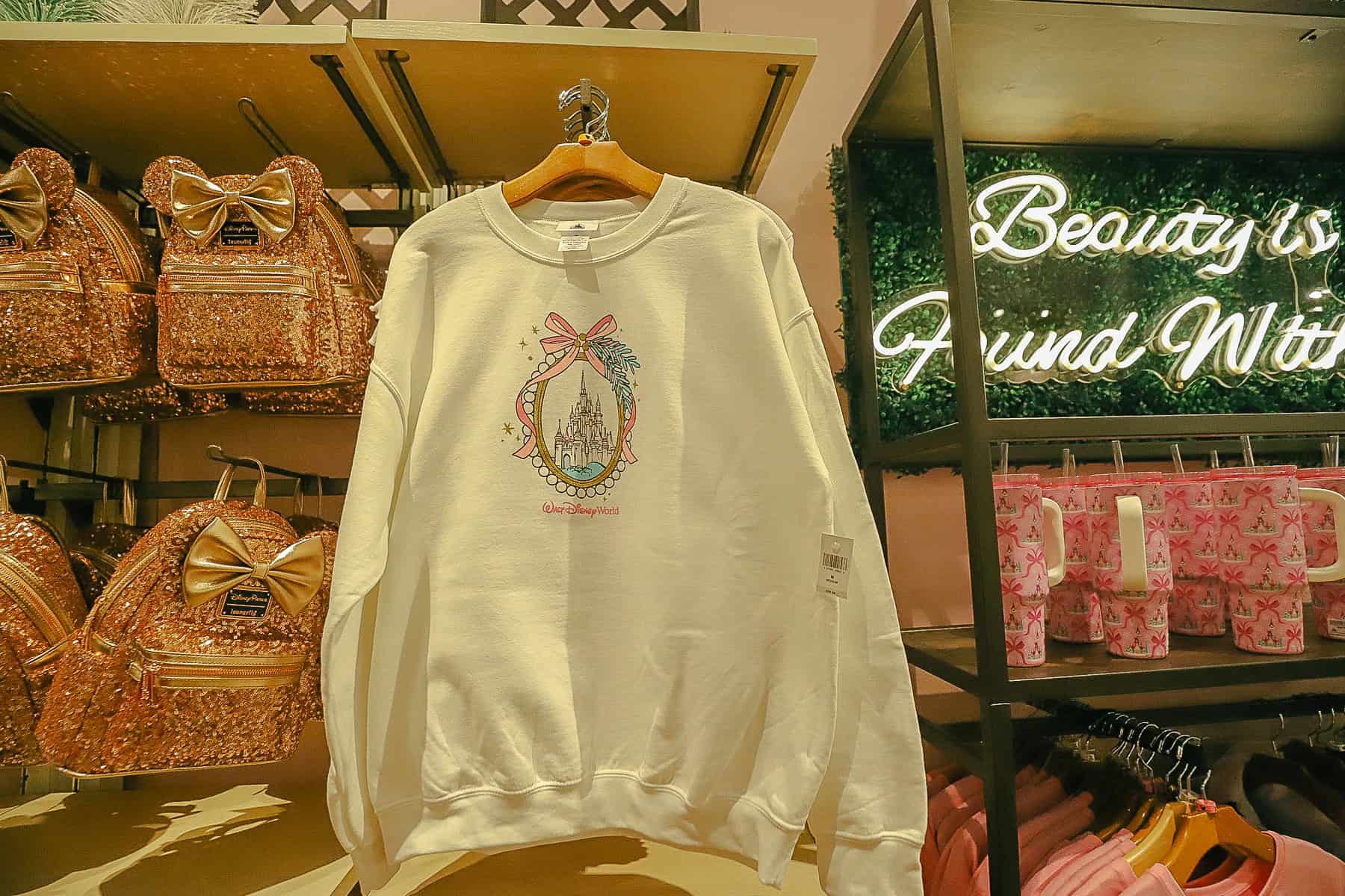 a white sweatshirt with a cameo featuring a pink bow and castle