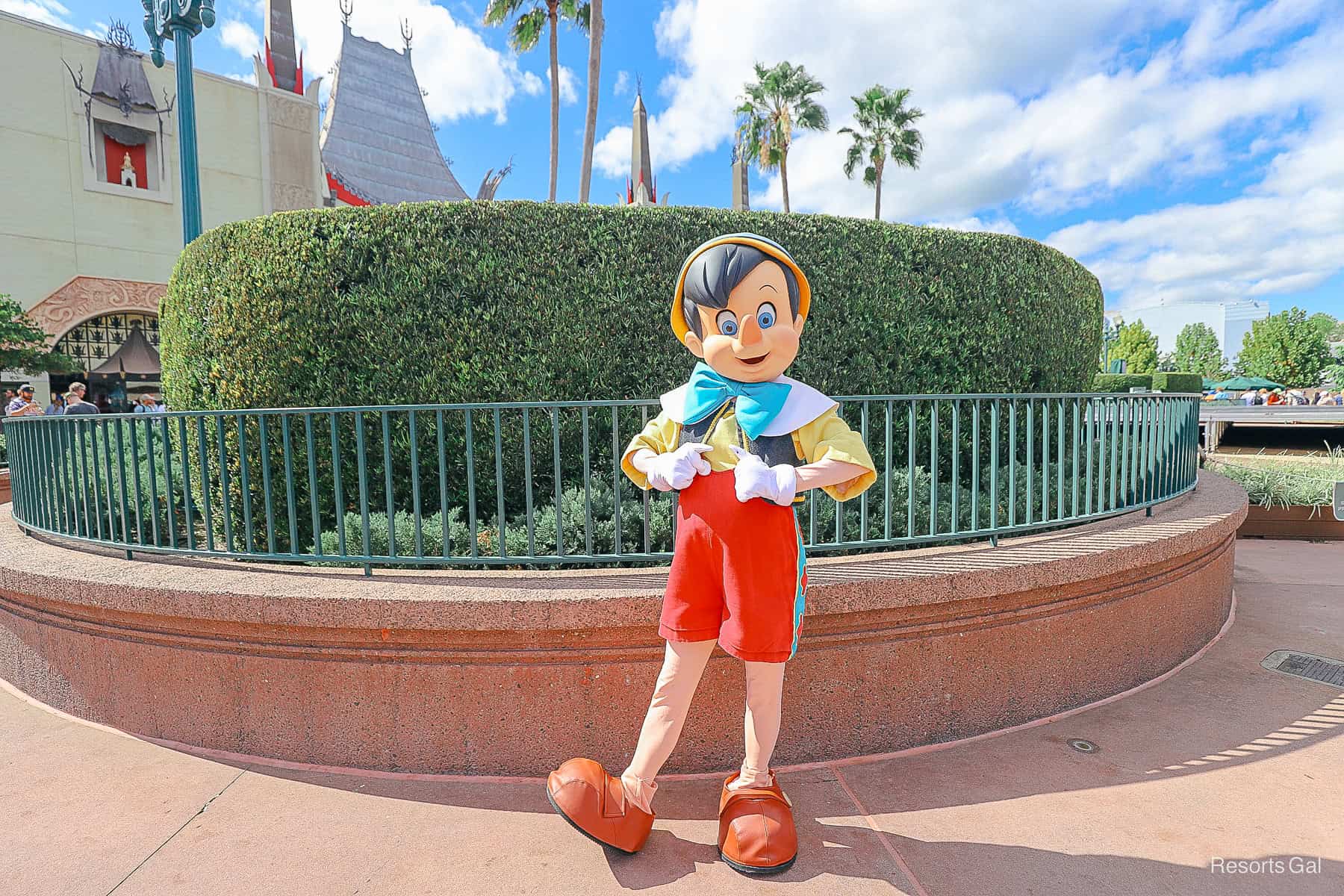 Pinocchio with red shorts, yellow shirt and blue bow poses to meet guests near Mickey and Minnie's Runaway Railway at Hollywood Studios