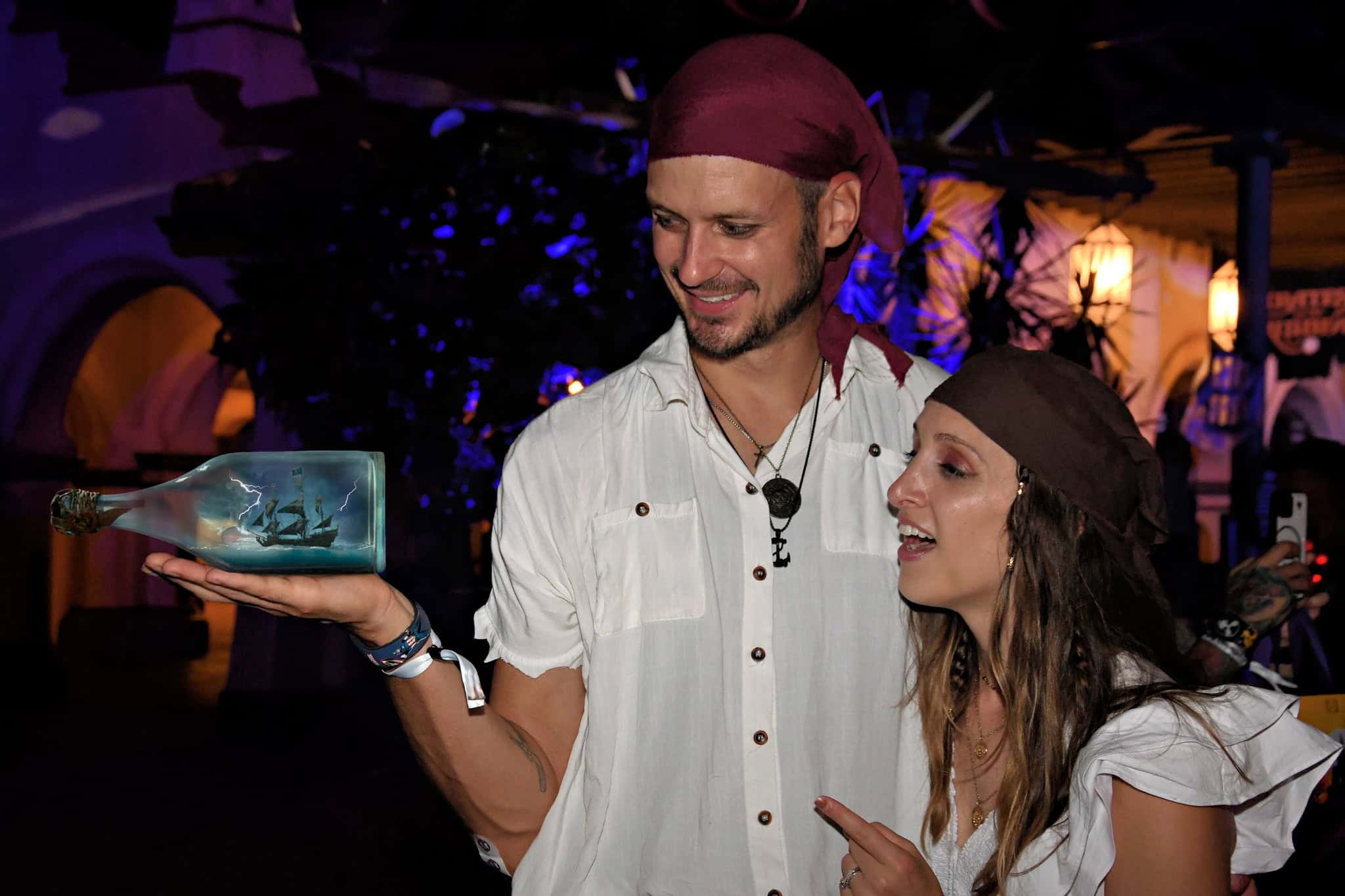 a couple dresses as pirates with a ship in a bottle photo opp 