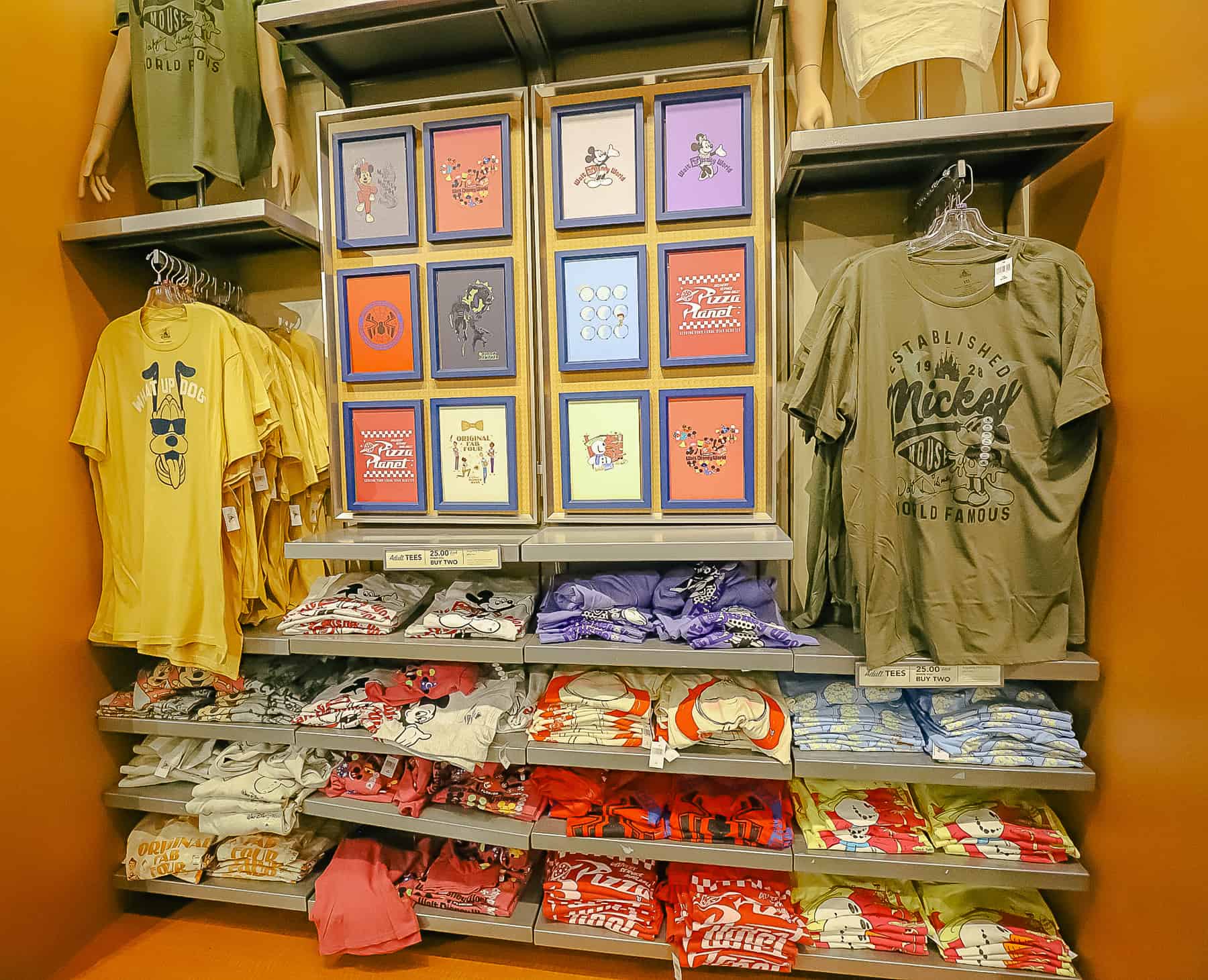 a wall of t-shirts with various Disney characters 
