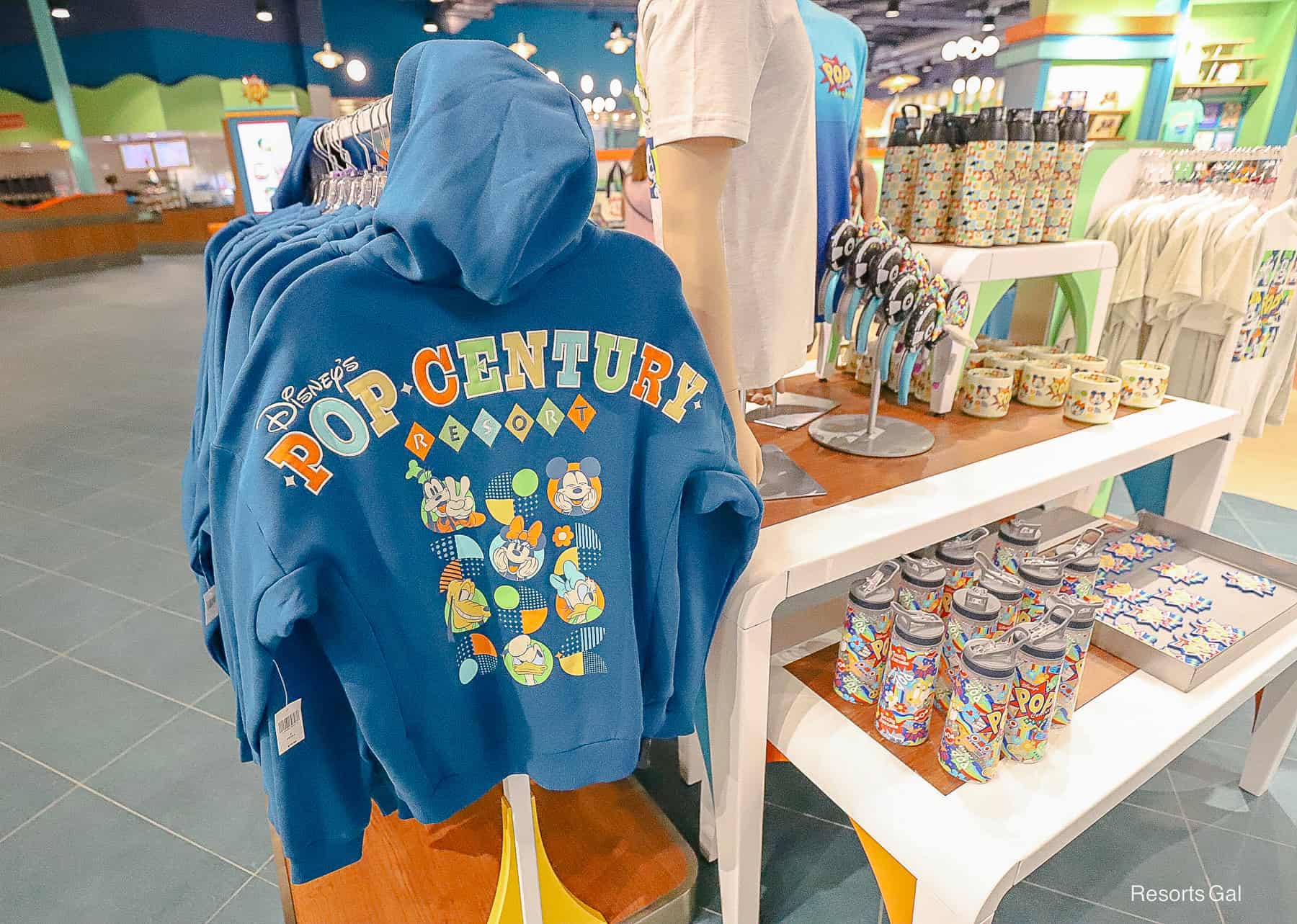 the back of a turquoise zip up jacket with the Pop Century Resort logo