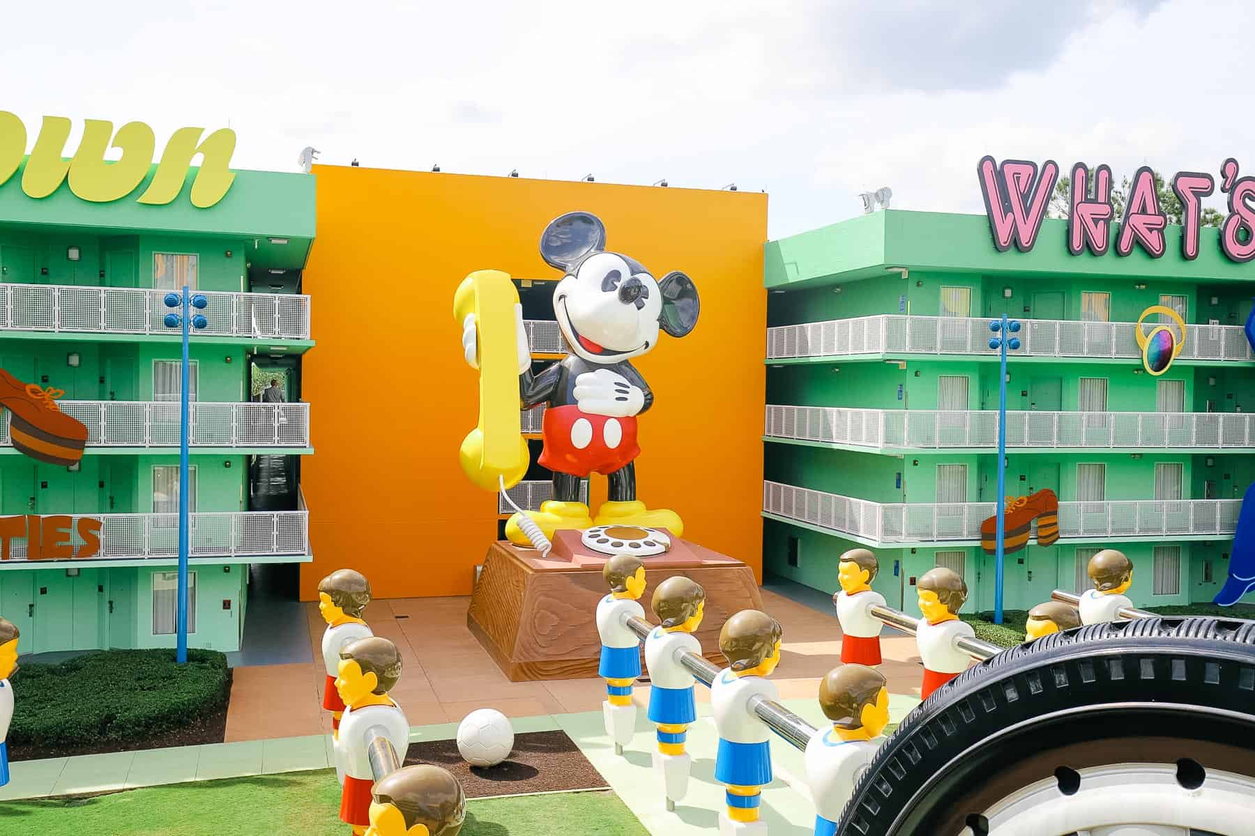 A rotary dial Mickey Mouse sits in the courtyard between two buildings at Pop Century Resort. 