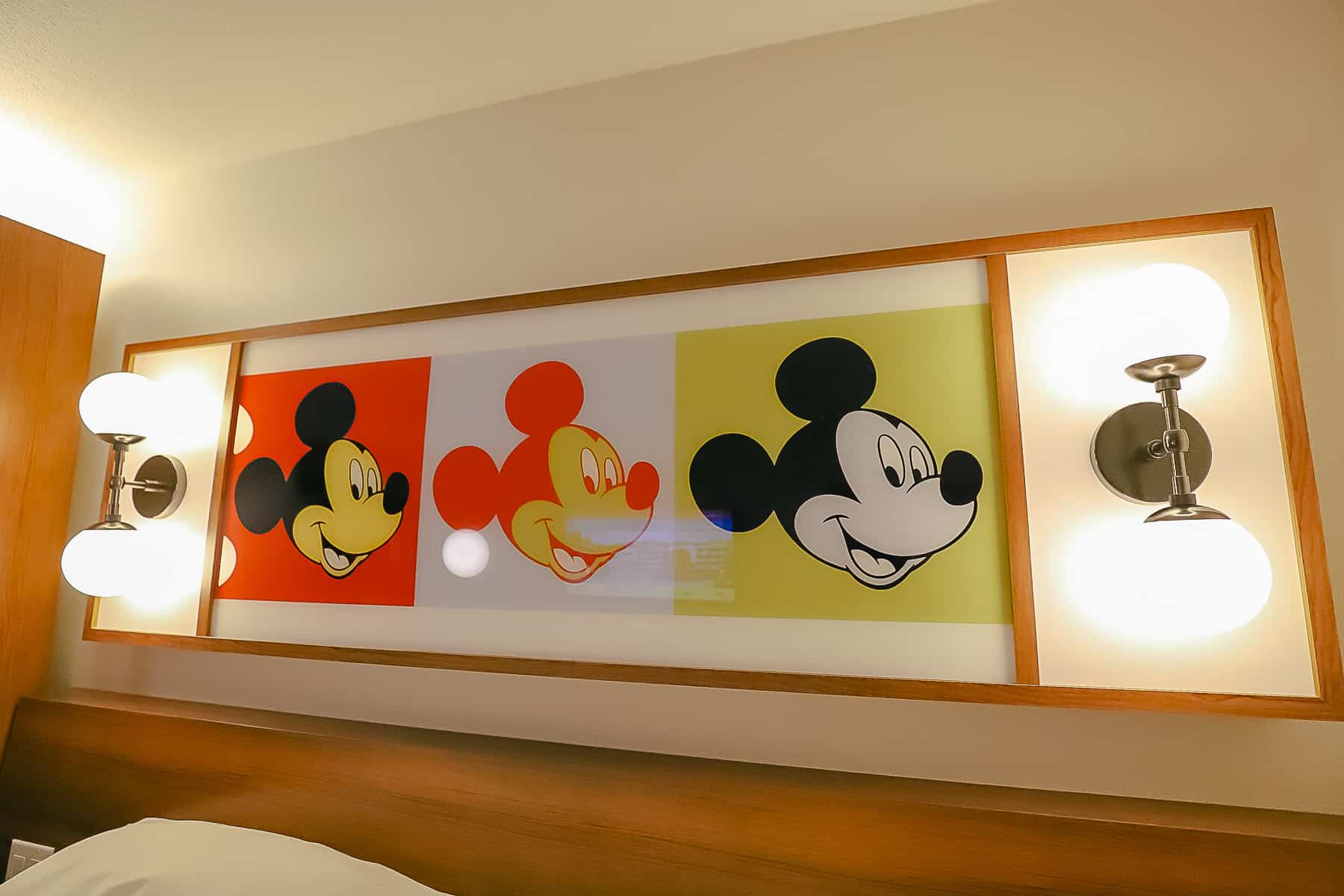 a piece of artwork with three Mickey Mouse's and light fixtures on each end 