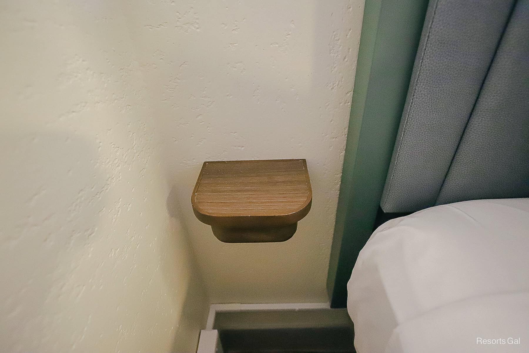 a small shelf on the far side of the bed for a phone or a beverage