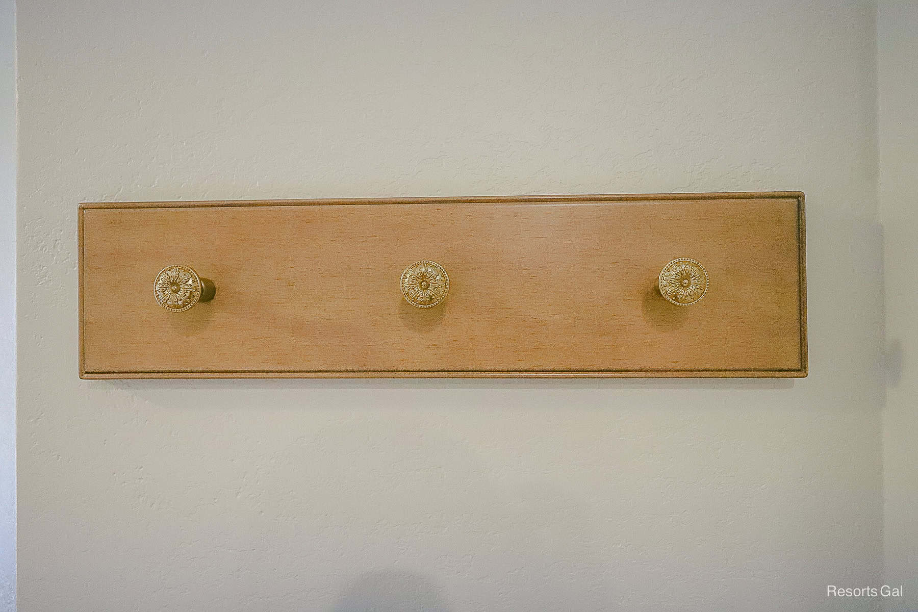 a wall mount with three decorative hooks for hanging jackets or clothing items