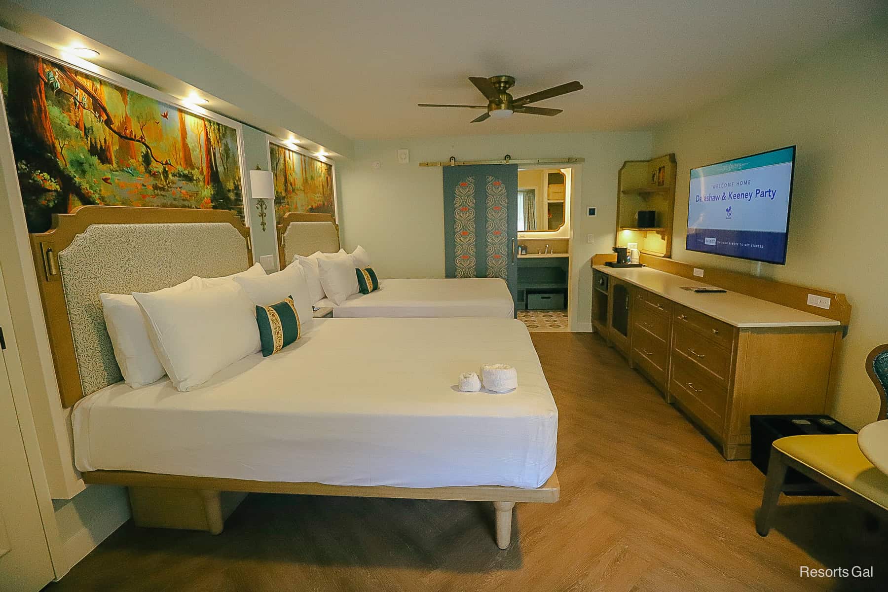 straight-facing view of two queen beds, dresser, and television