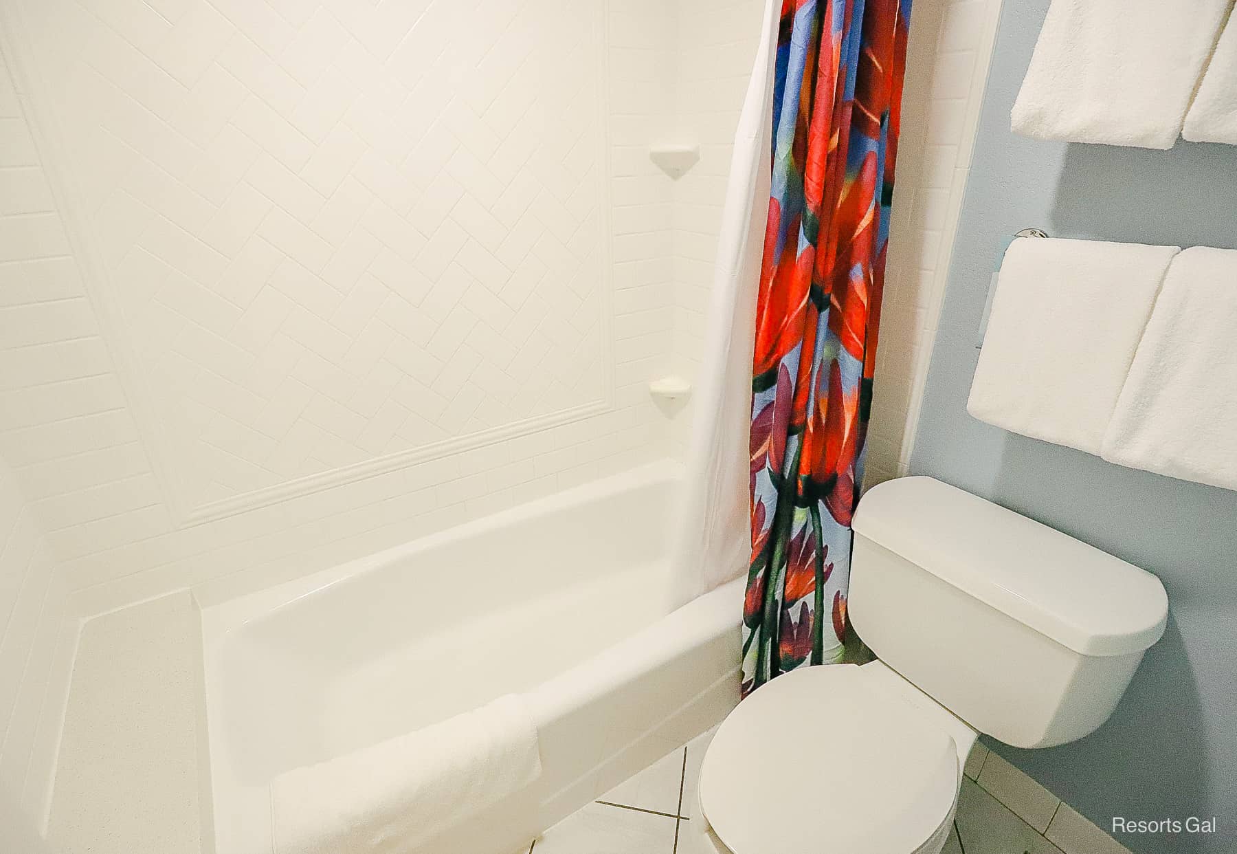 a bath and tub shower combination with a bright shower curtain 