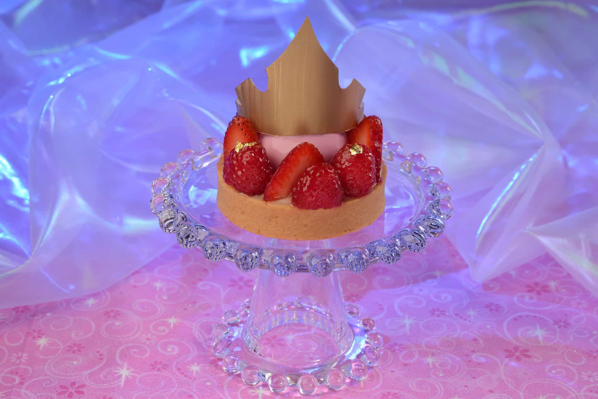 a fruit tart with berries and a gold crown 