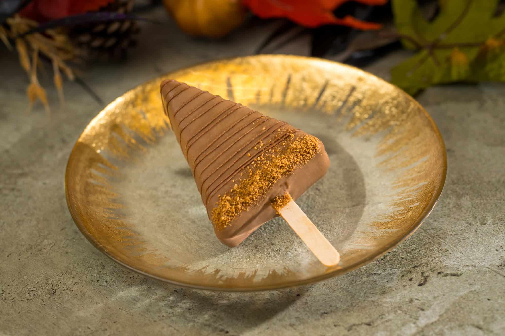a triangle popsicle that's coated in chocolate with a chocolate drizzle