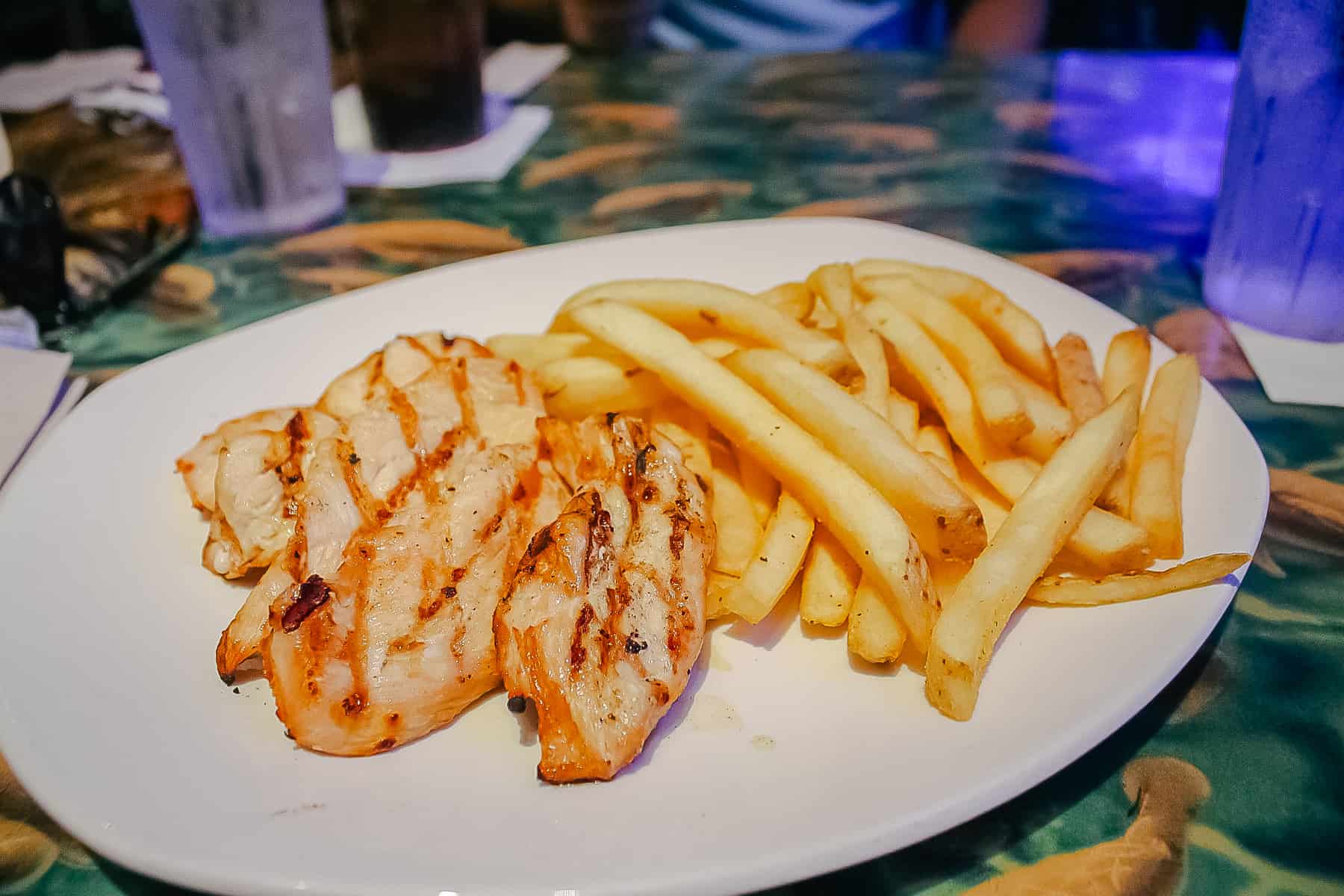 An allergy friendly meal of grilled chicken fingers with fries prepared by a chef at Rainforest Cafe at Disney Springs. 
