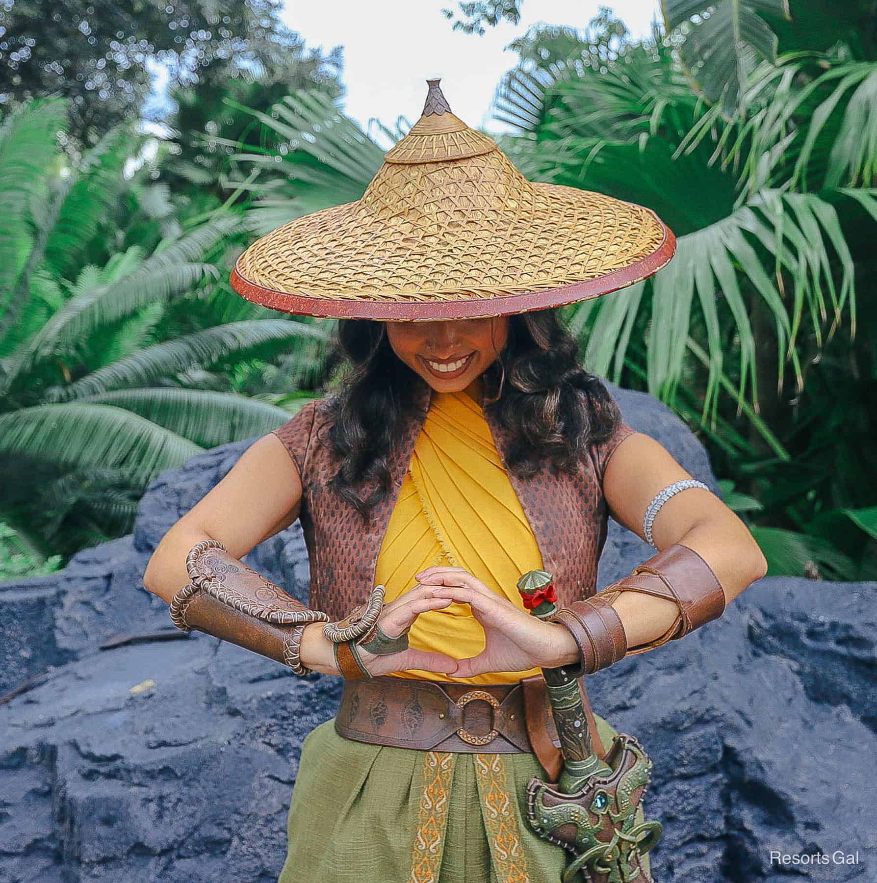 Raya poses with head bent and hands in circle hands gesture meaning Kumandra forever. 