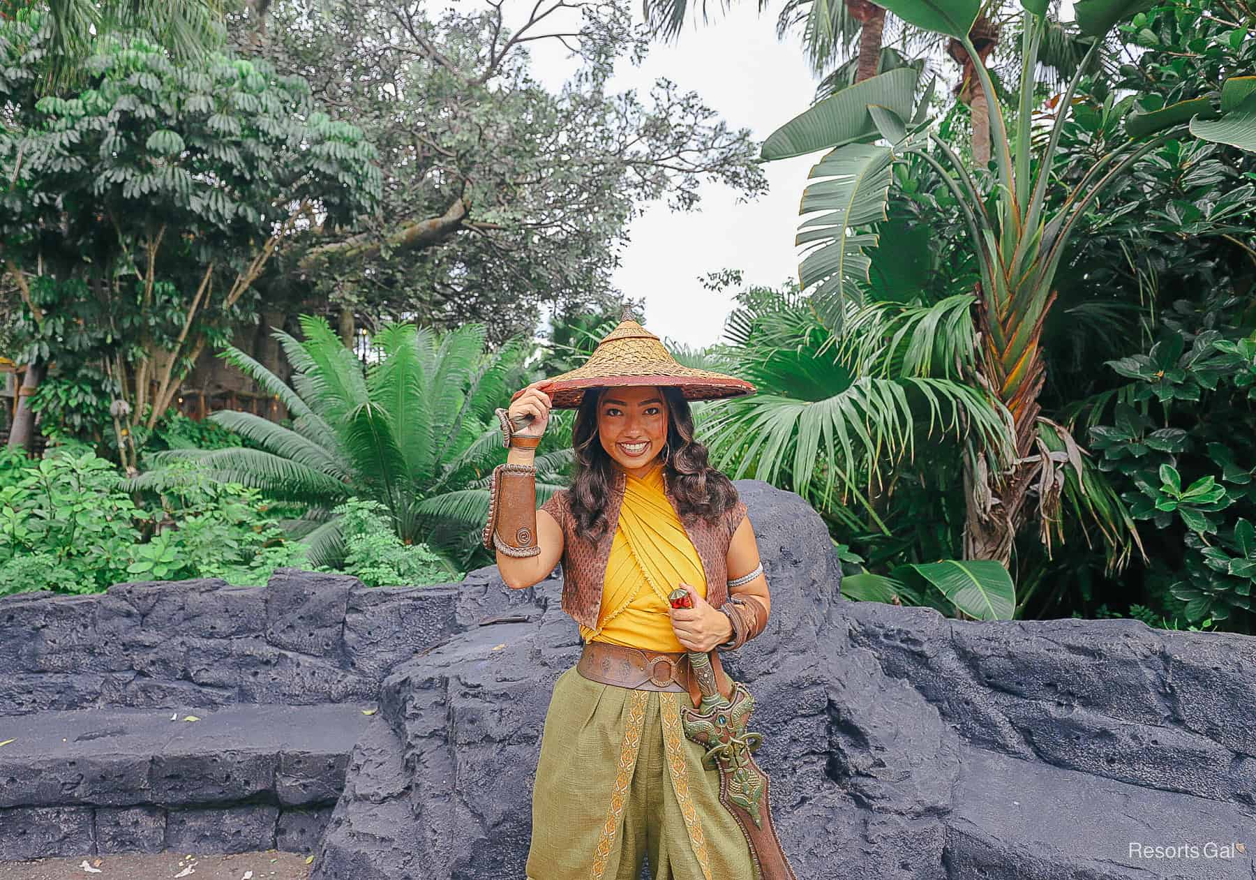Raya tips hat for the camera with hand on her dragon blade. 