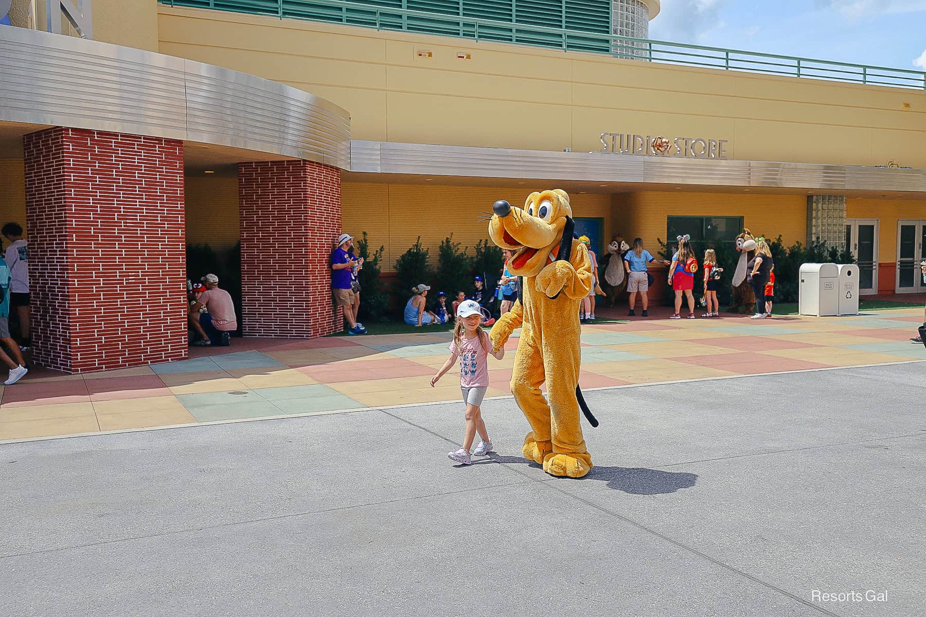 Pluto walking the lot at Hollywood Studios with a child