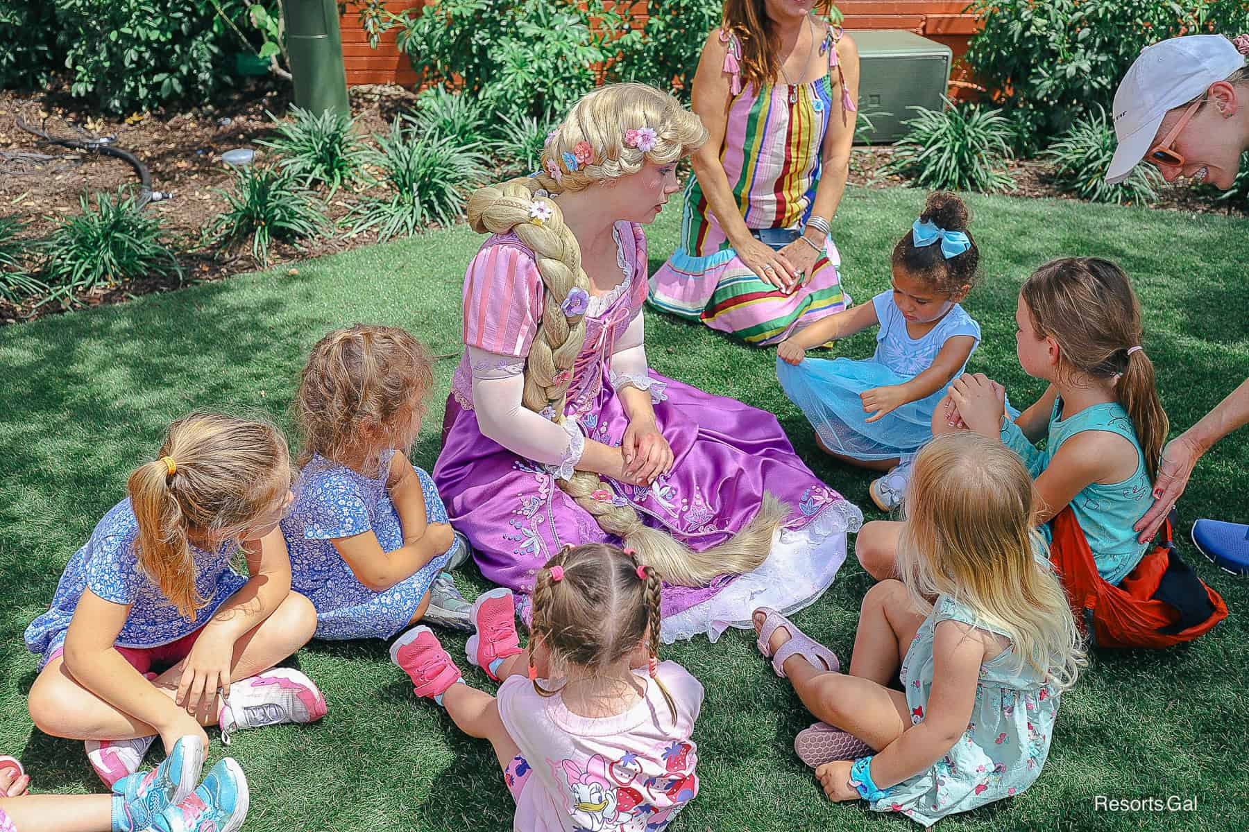 Rapunzel interacting with younger guests on a green lawn.
