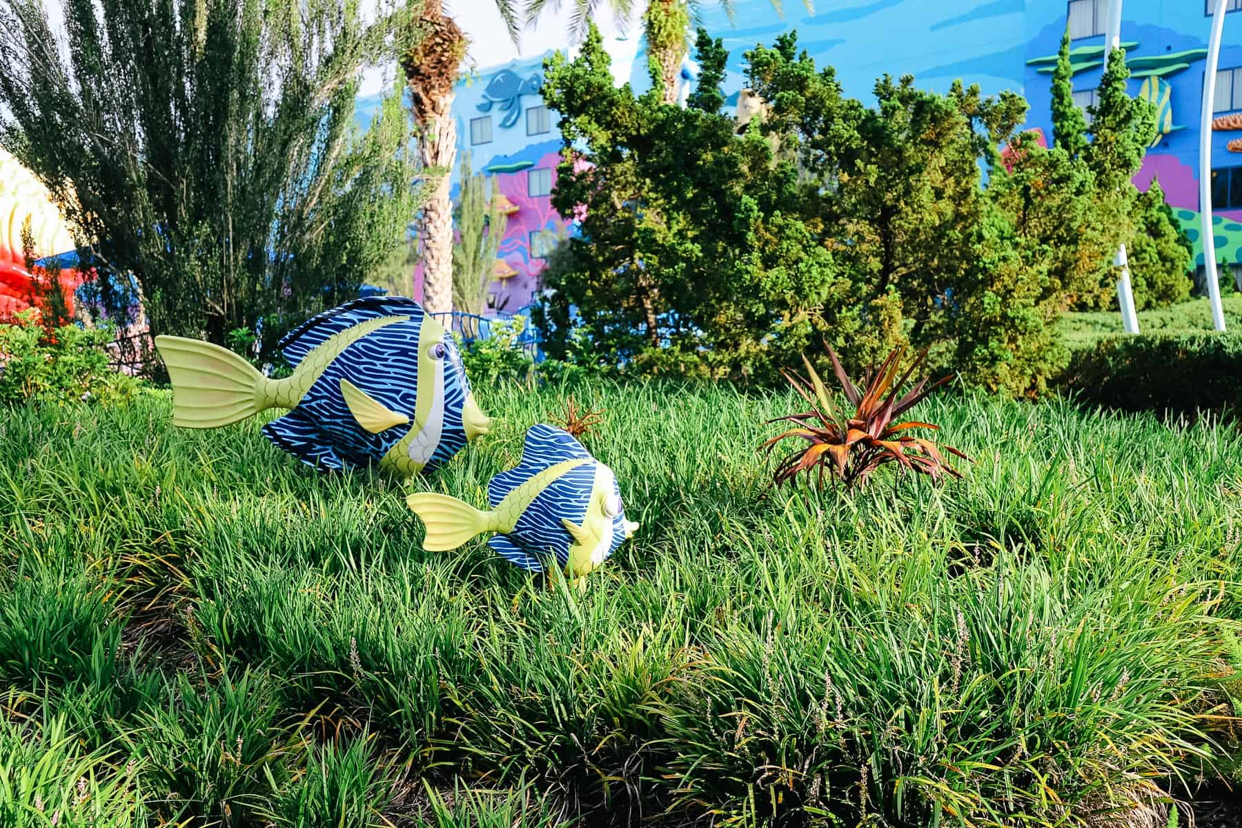 Blue and yellow decorative fish in large green grass meant to resemble the sea. 
