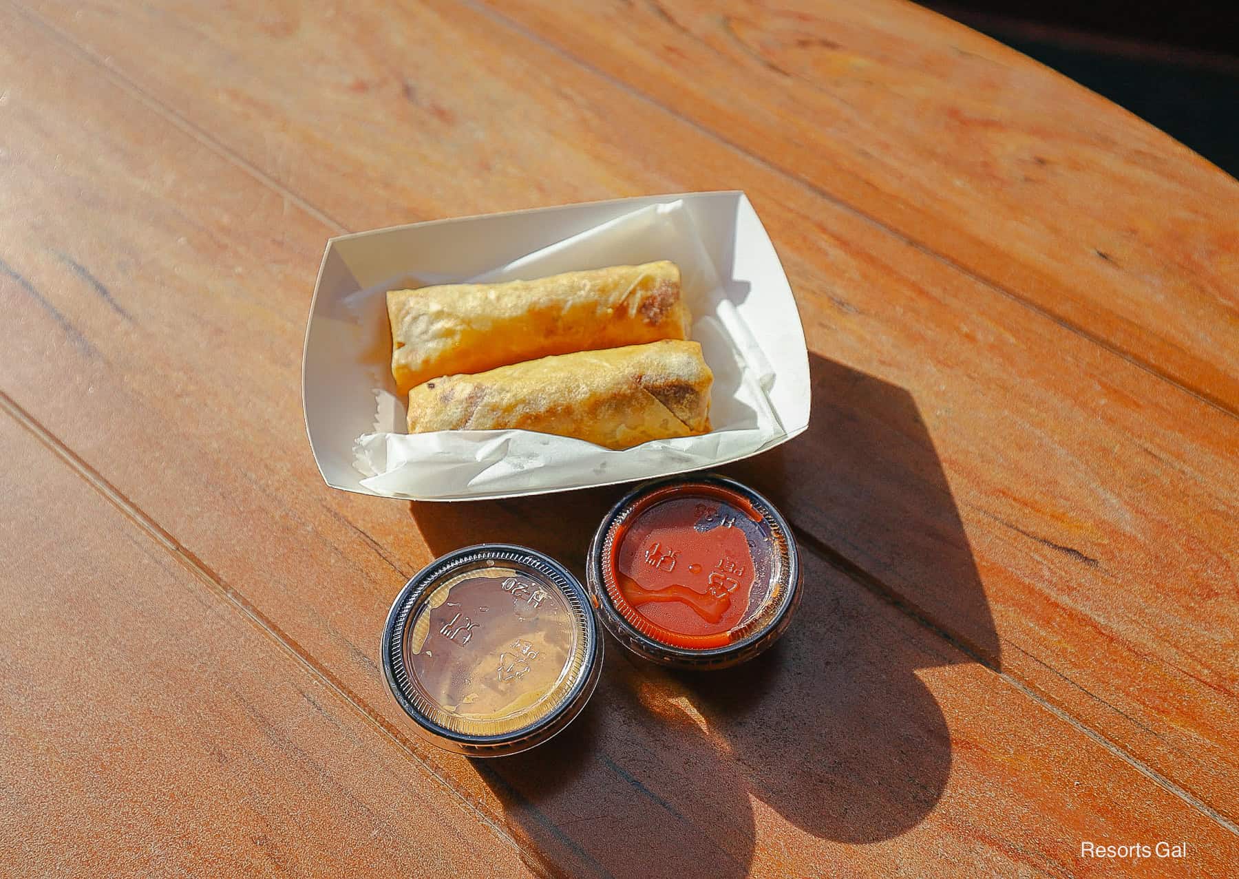 two spring rolls on a table with two sauces 