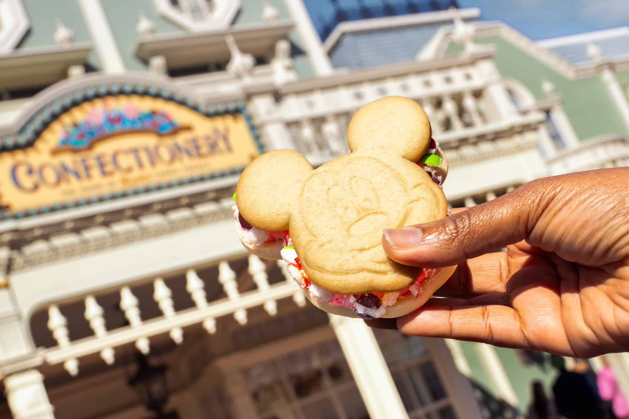 a hand holding a Mickey sugar cookie sandwich