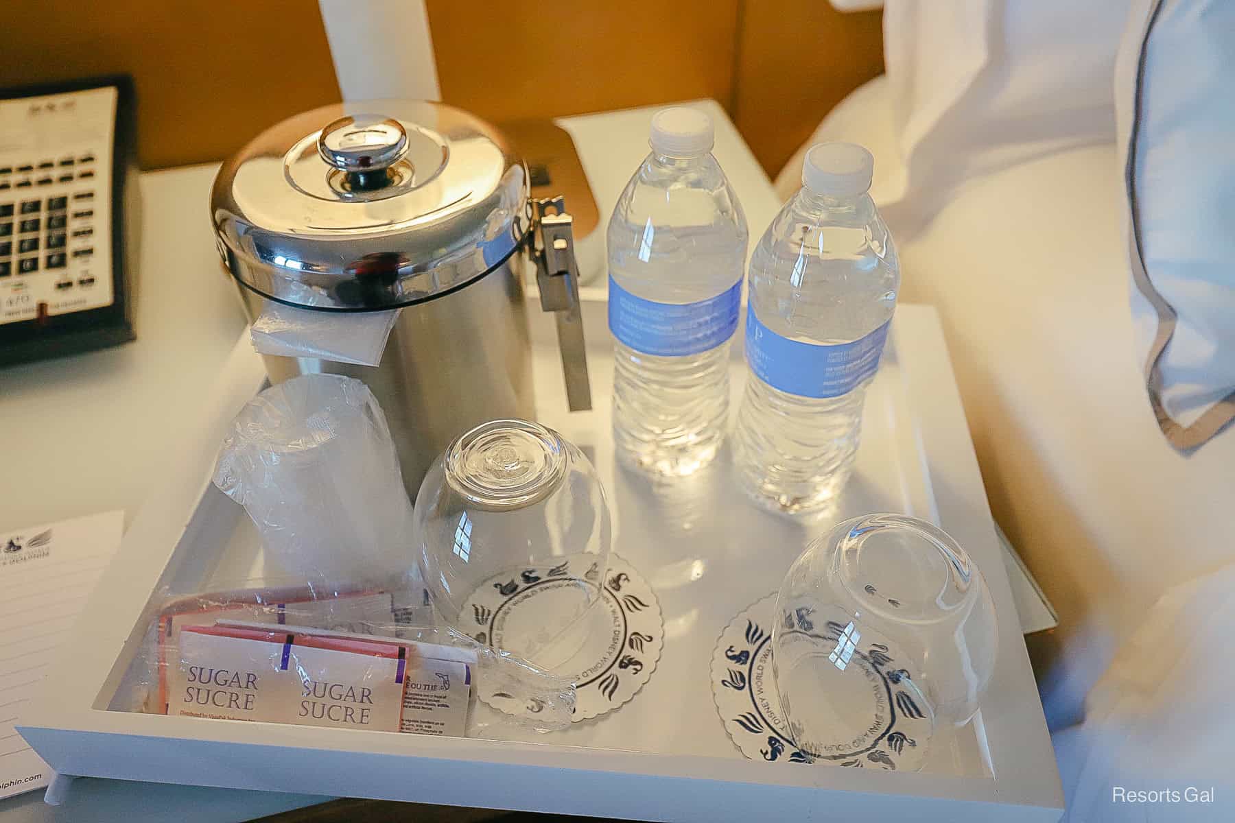 a tray with bottled water, glasses, and an ice bucket 