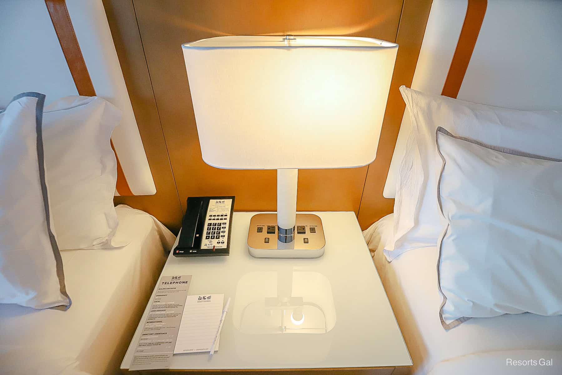 a lamp on a nightstand between the beds 