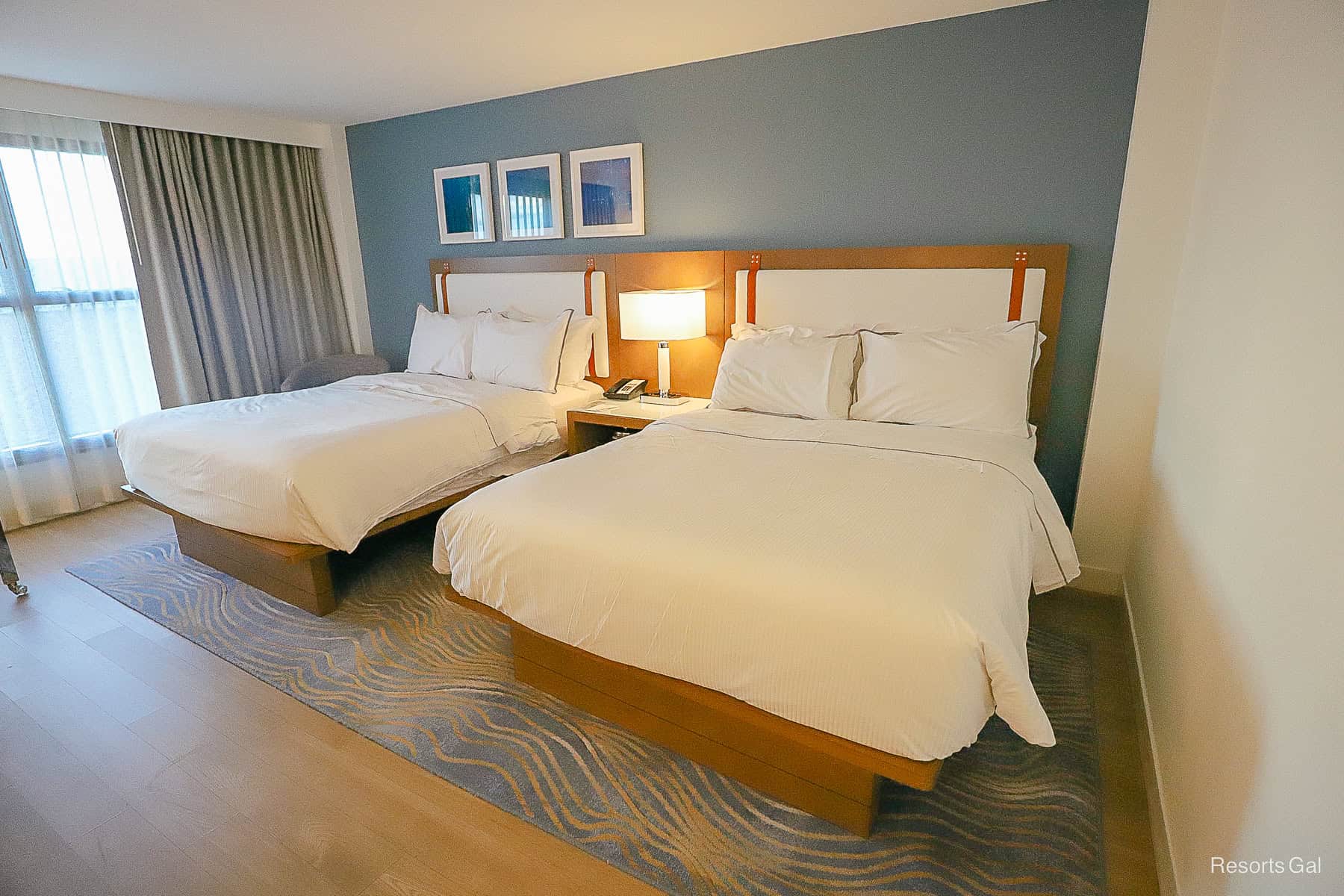 the two beds sit on a blue accent wall with an extended headboard stretching between them 