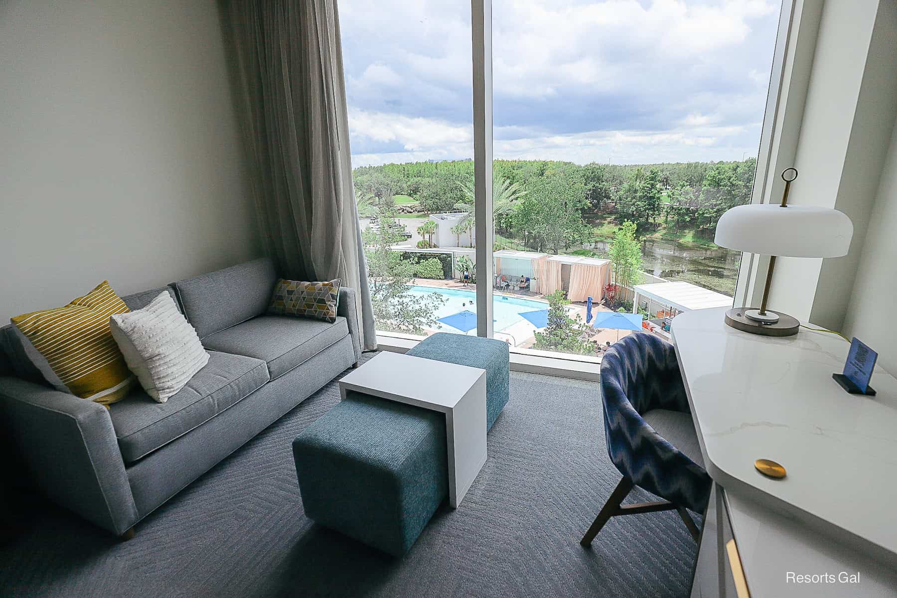 the living space in the hotel room with a sofa and desk chair