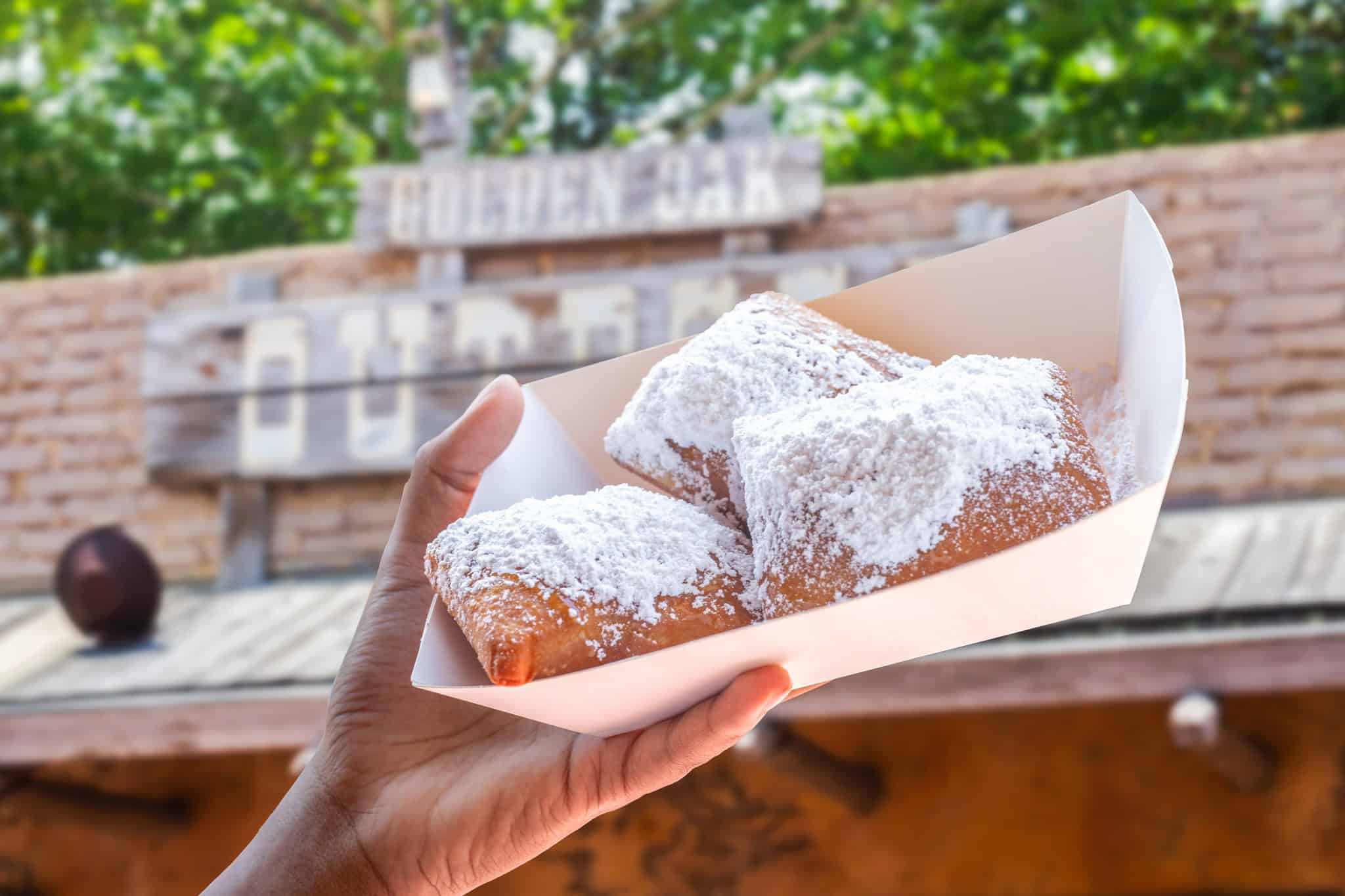 a tray with three beignets topped with powder sugar 