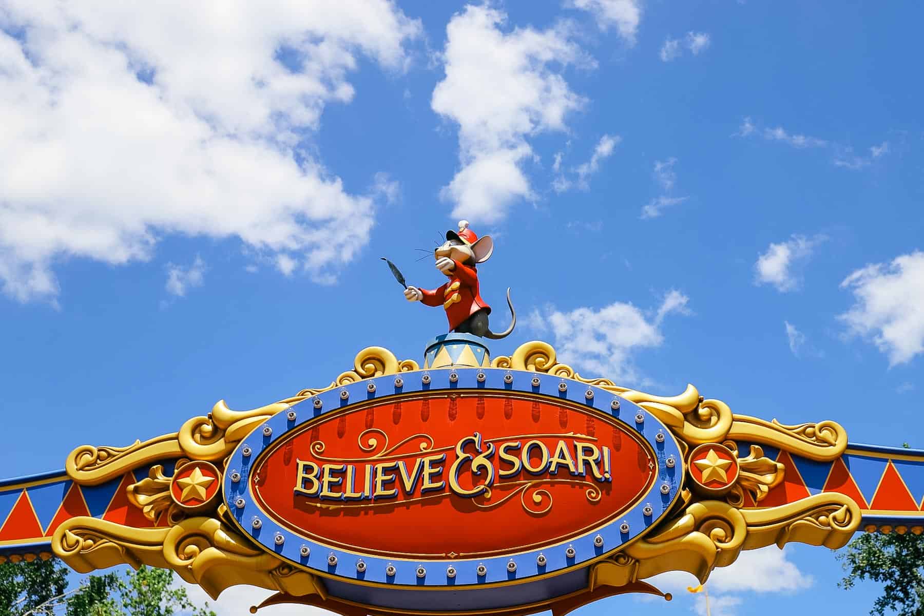 Timothy Mouse over the entrance of a sign that reads Believe and Soar. 