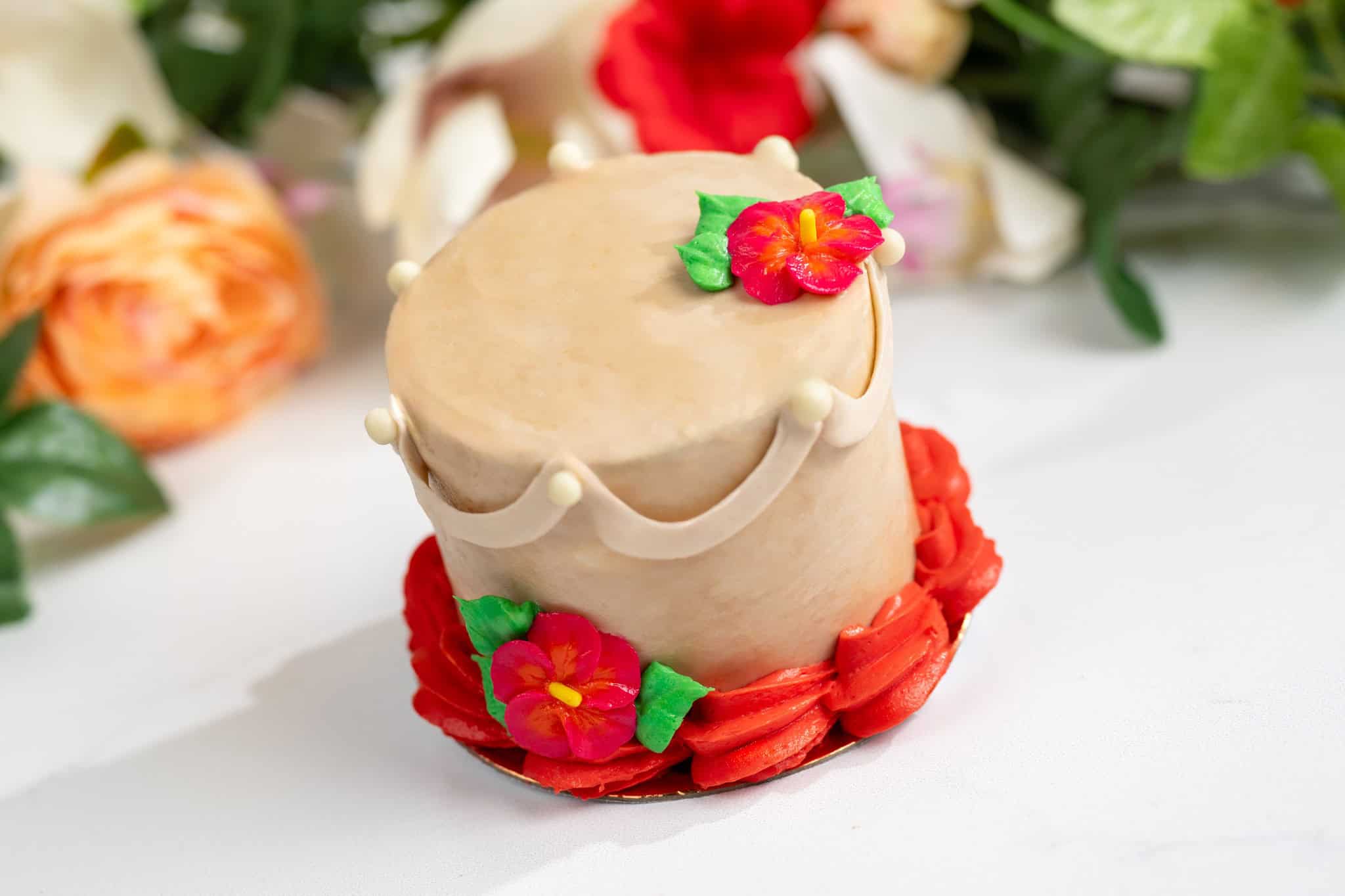 a tan cake with red Hawaiian flowers 