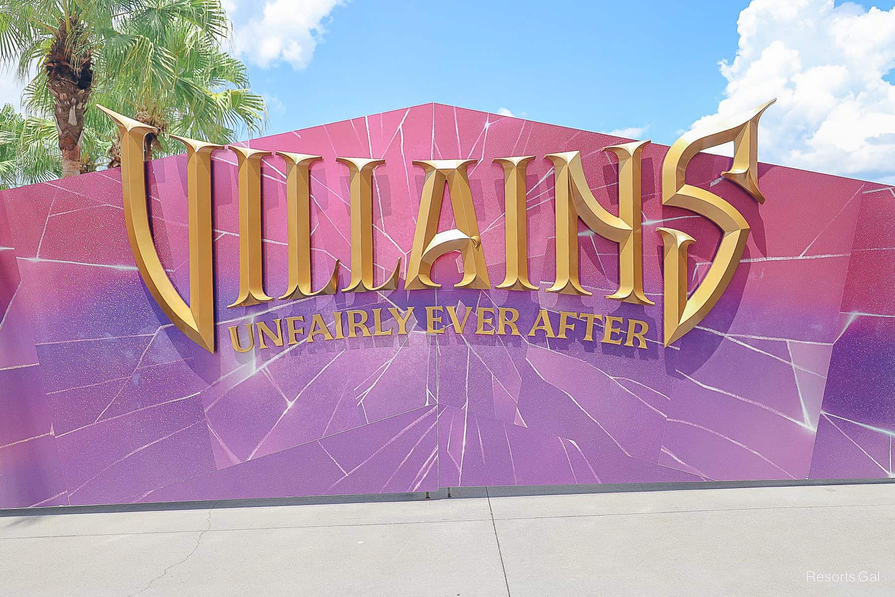 a sign with a pink and purple backdrop that has Disney Villains: Unfairly Ever After in gold letters 