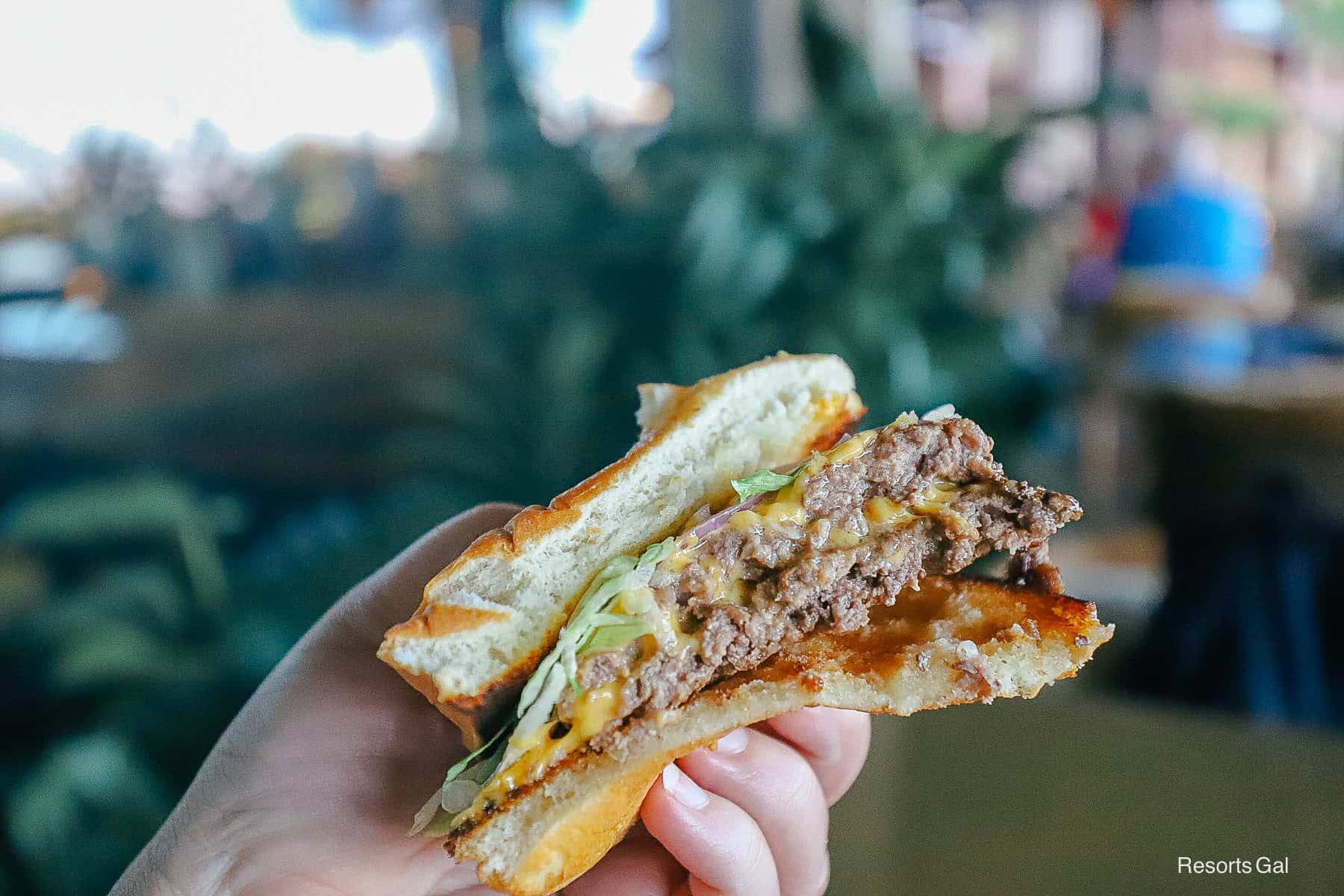 a hand holding the burger cut in half to see the inside 