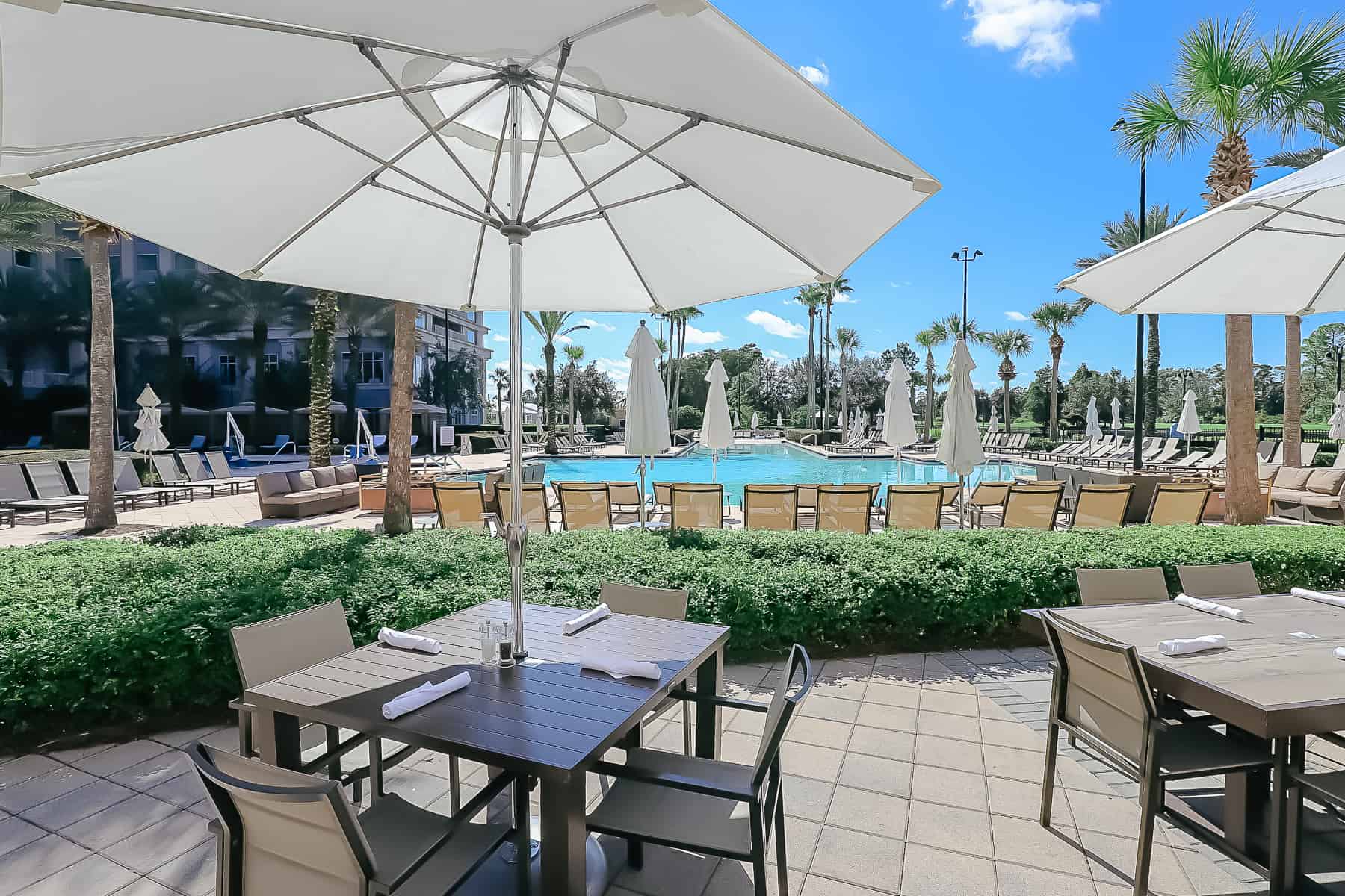 umbrellas over tables and chairs looking on to the Waldorf Astoria Orlando's Pool